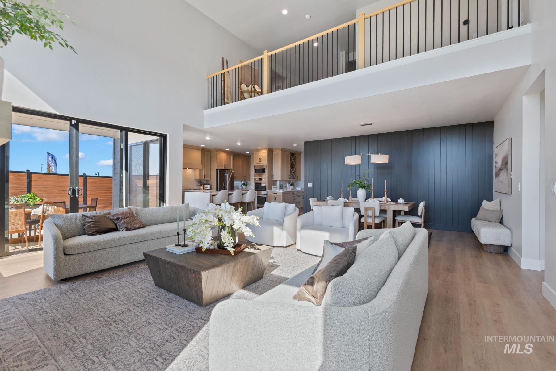 Living area with light wood-style flooring, an accent wall, recessed lighting, and a high ceiling