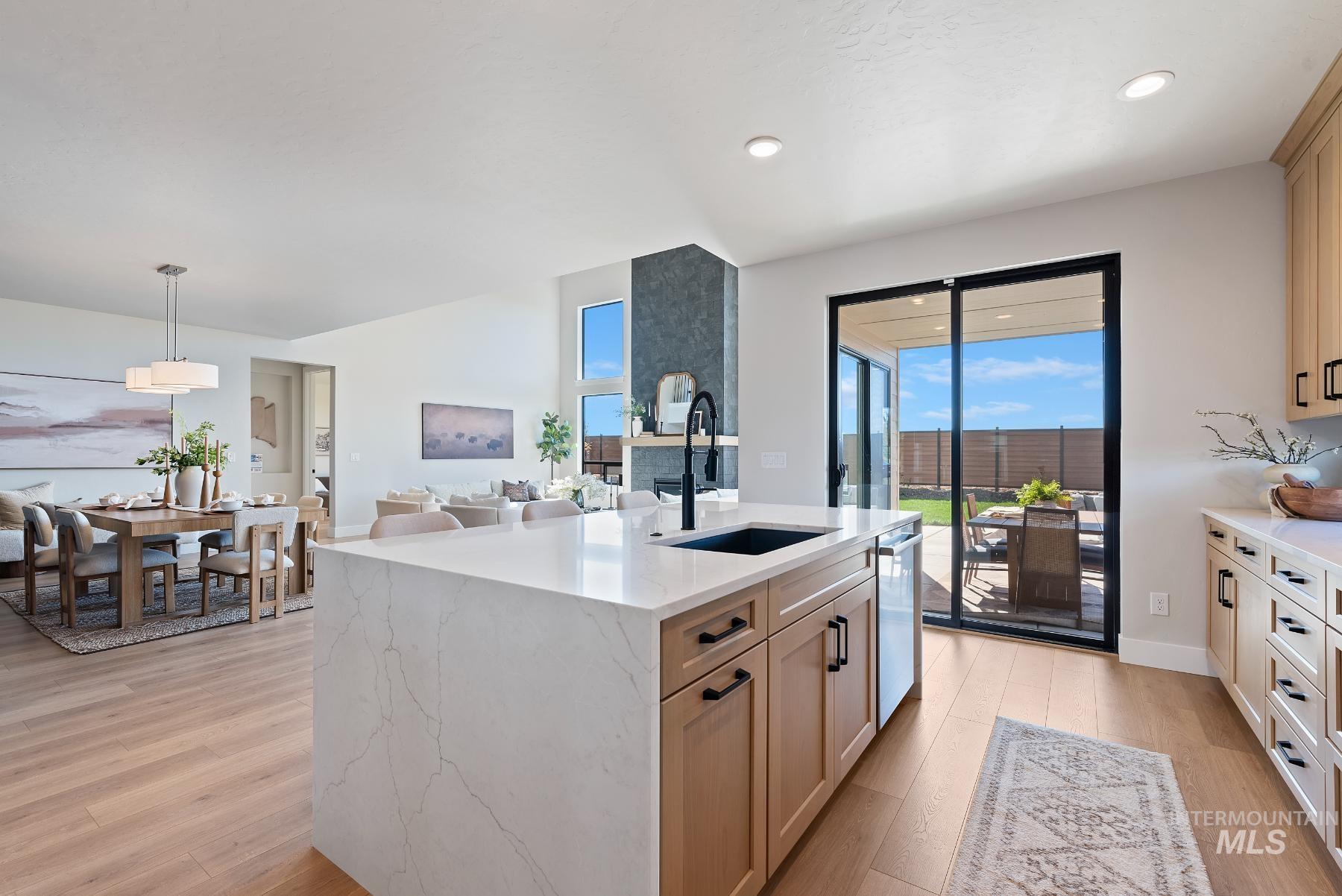 Kitchen featuring open floor plan, light stone counters, light wood-style flooring, pendant lighting, and healthy amount of natural light