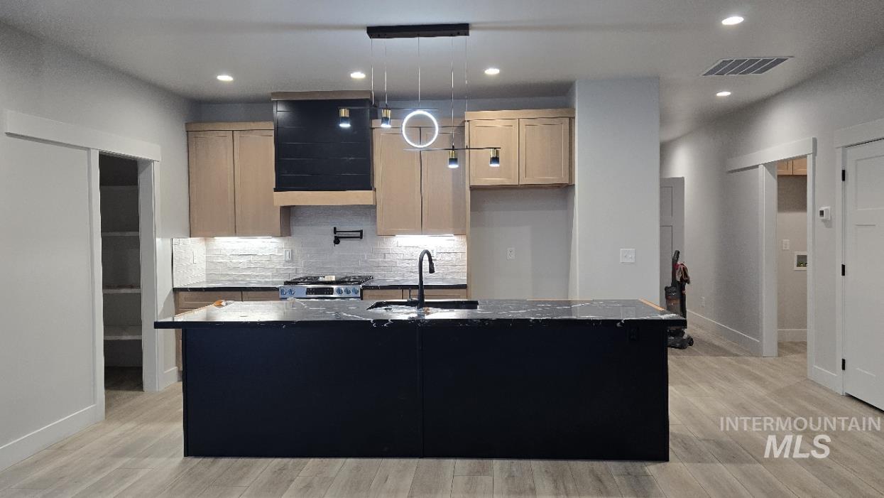 Kitchen with dark cabinetry, tasteful backsplash, pendant lighting, recessed lighting, and extractor fan