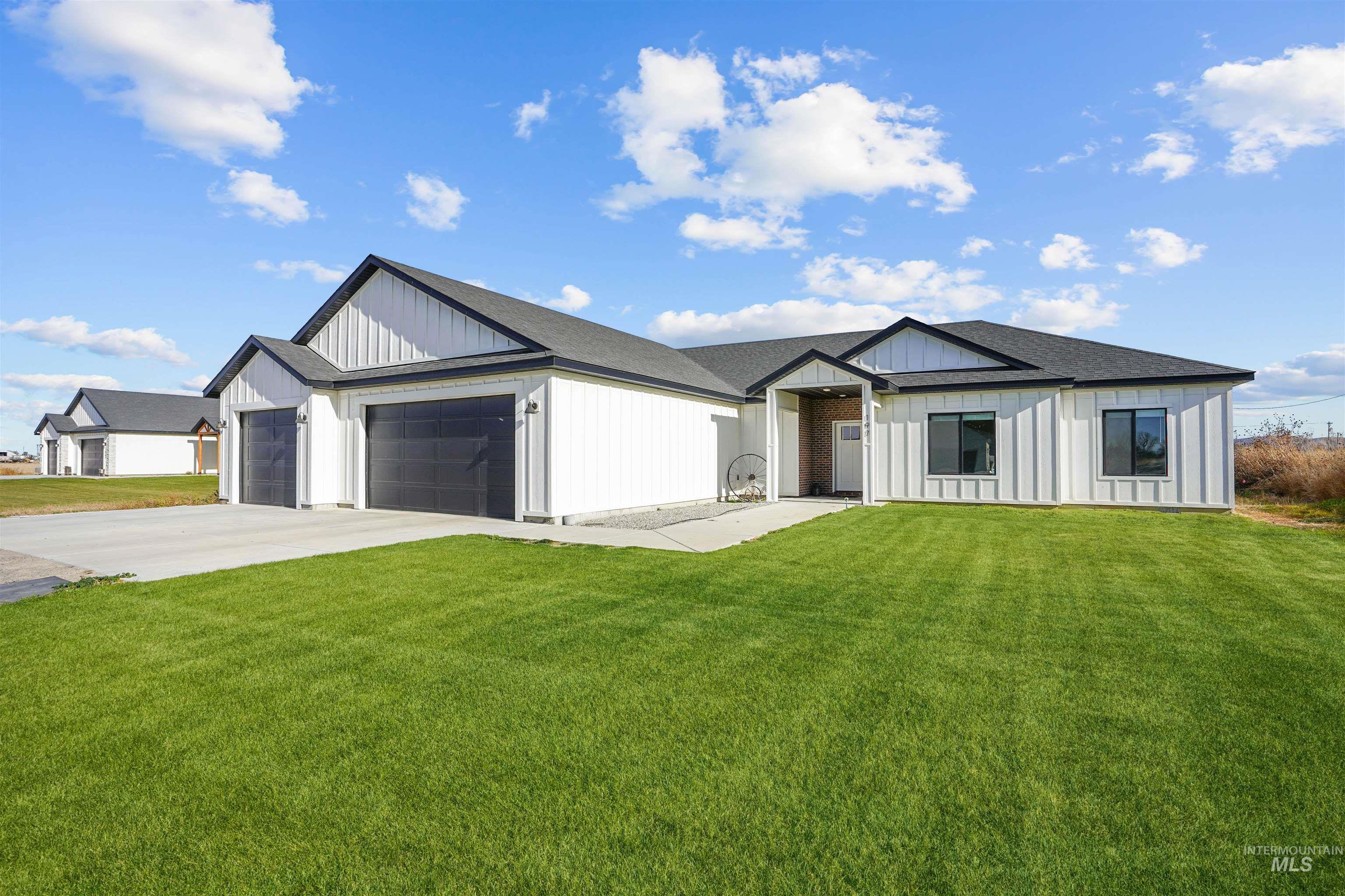 Modern farmhouse style home featuring a front lawn, an attached garage, board and batten siding, and driveway