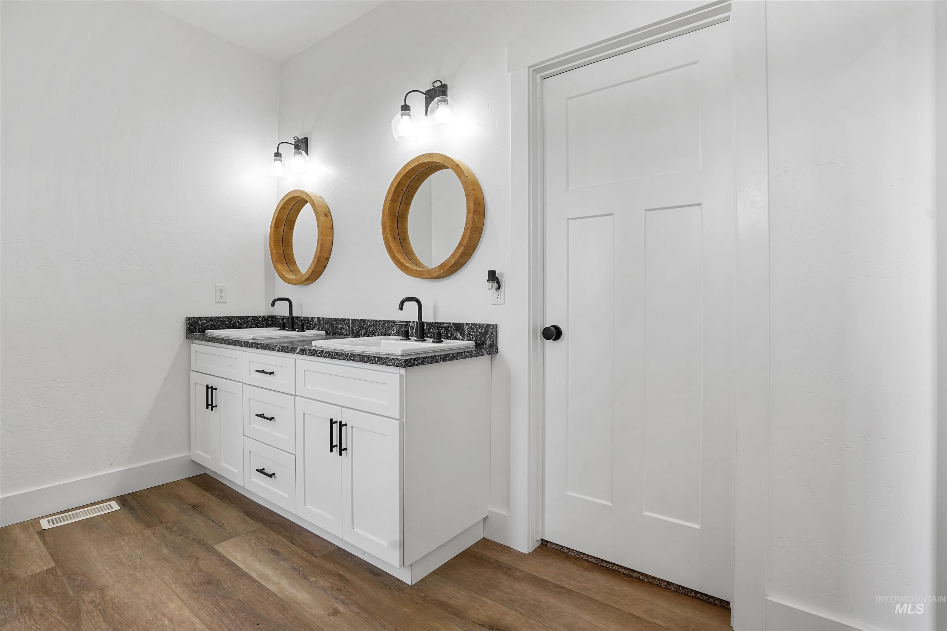 Bathroom featuring double vanity and dark wood-type flooring
