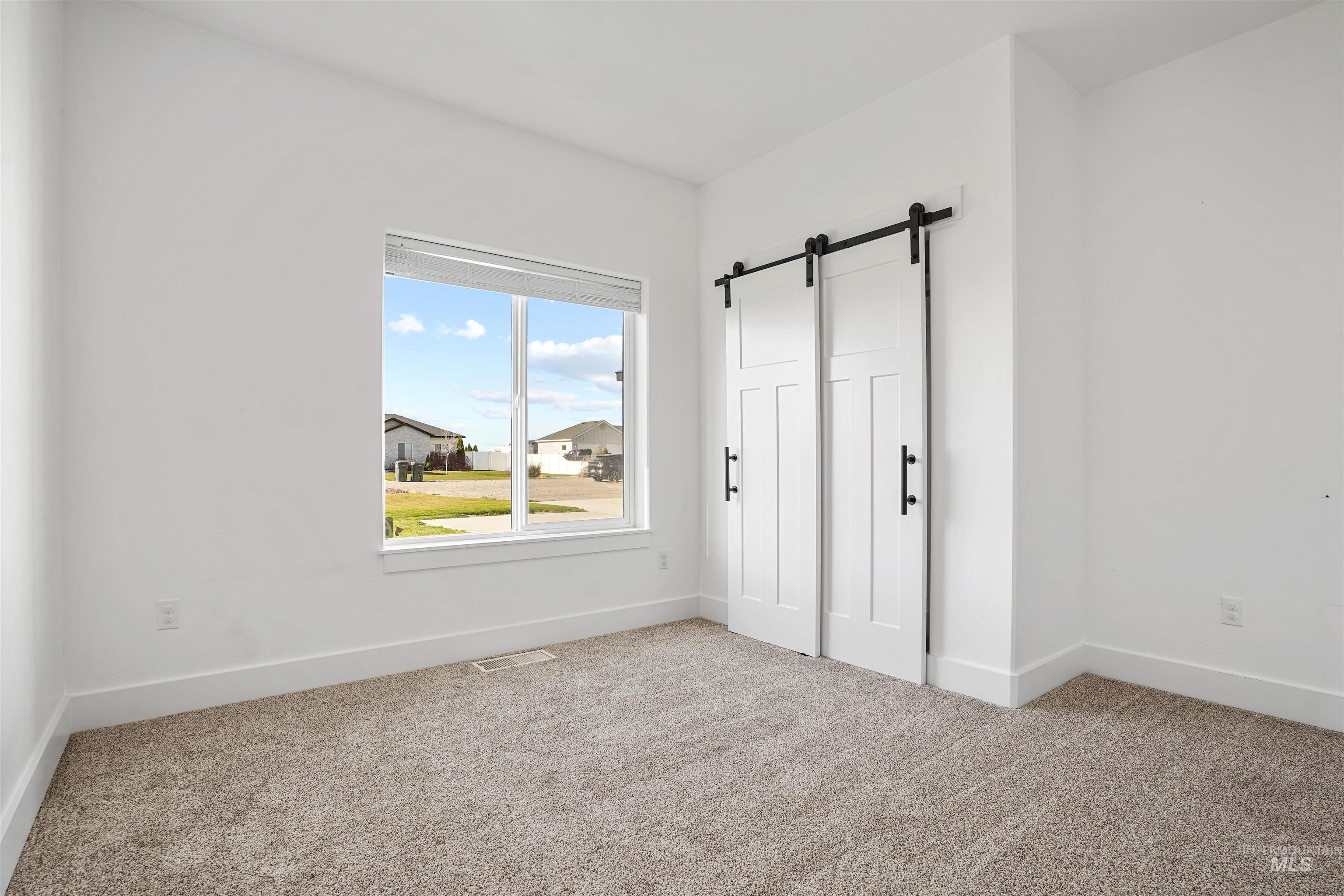 Unfurnished bedroom with a barn door and carpet floors