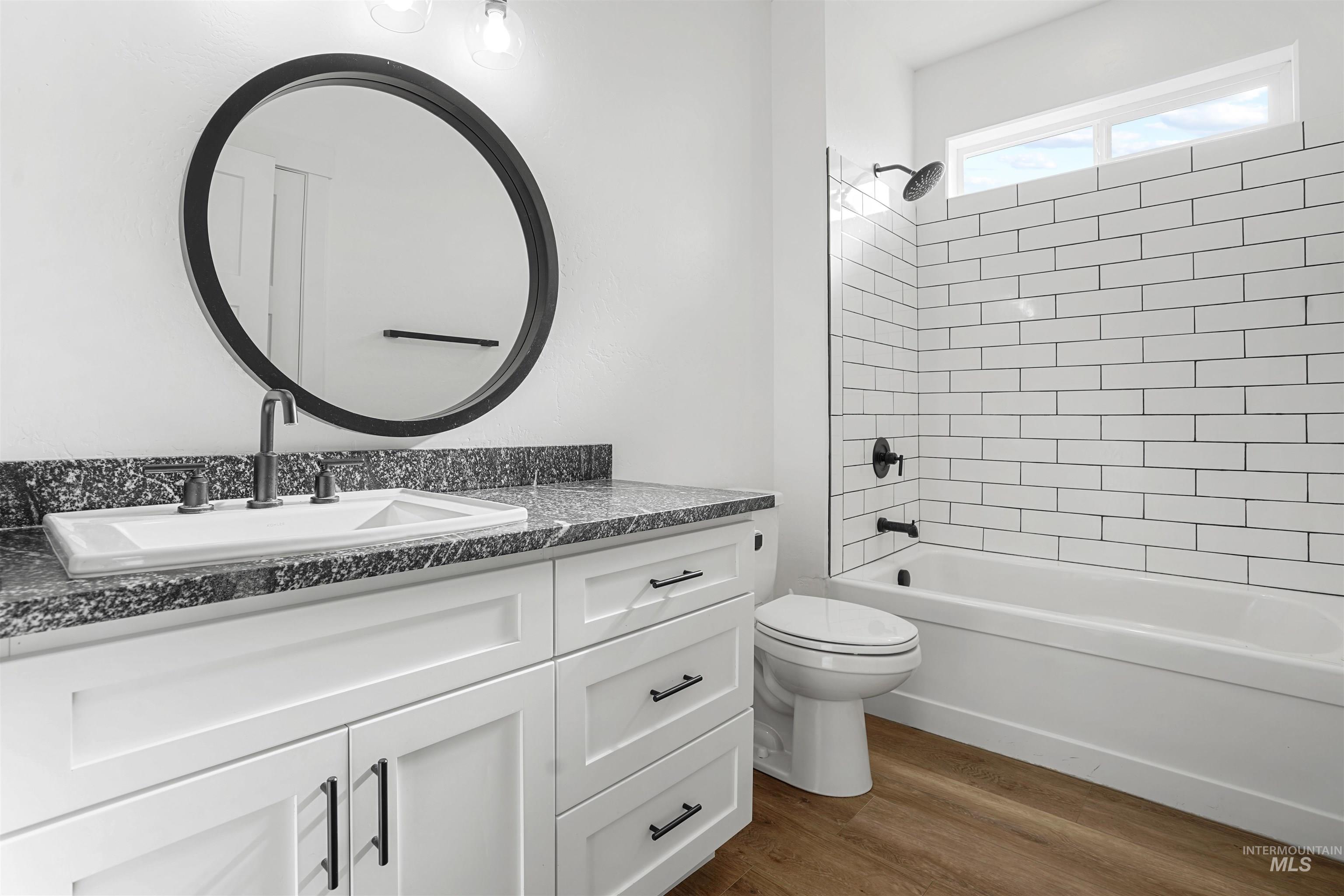 Bathroom featuring shower / tub combination, dark wood-style floors, and vanity
