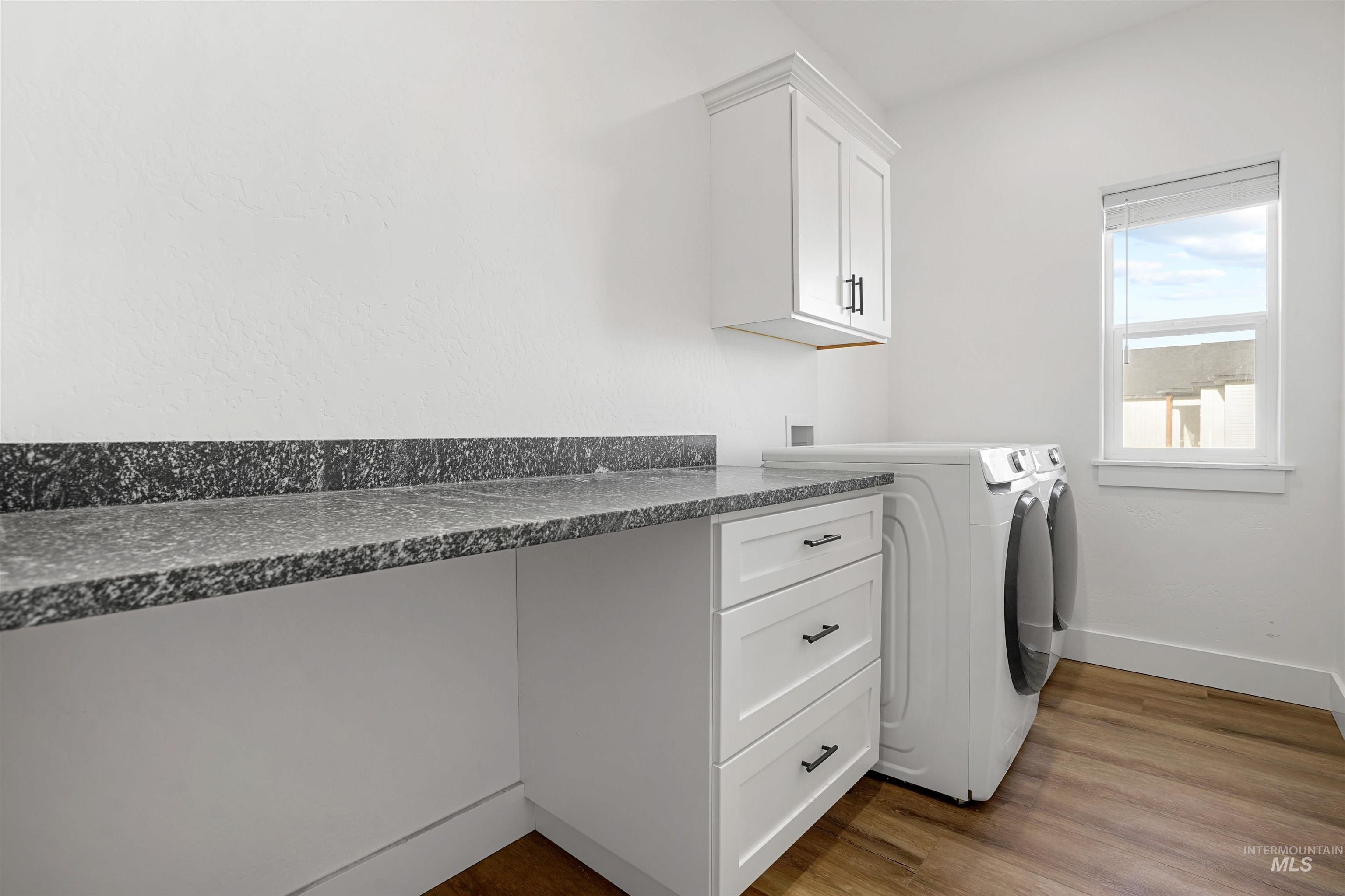 Washroom with dark wood-type flooring, separate washer and dryer, and cabinet space