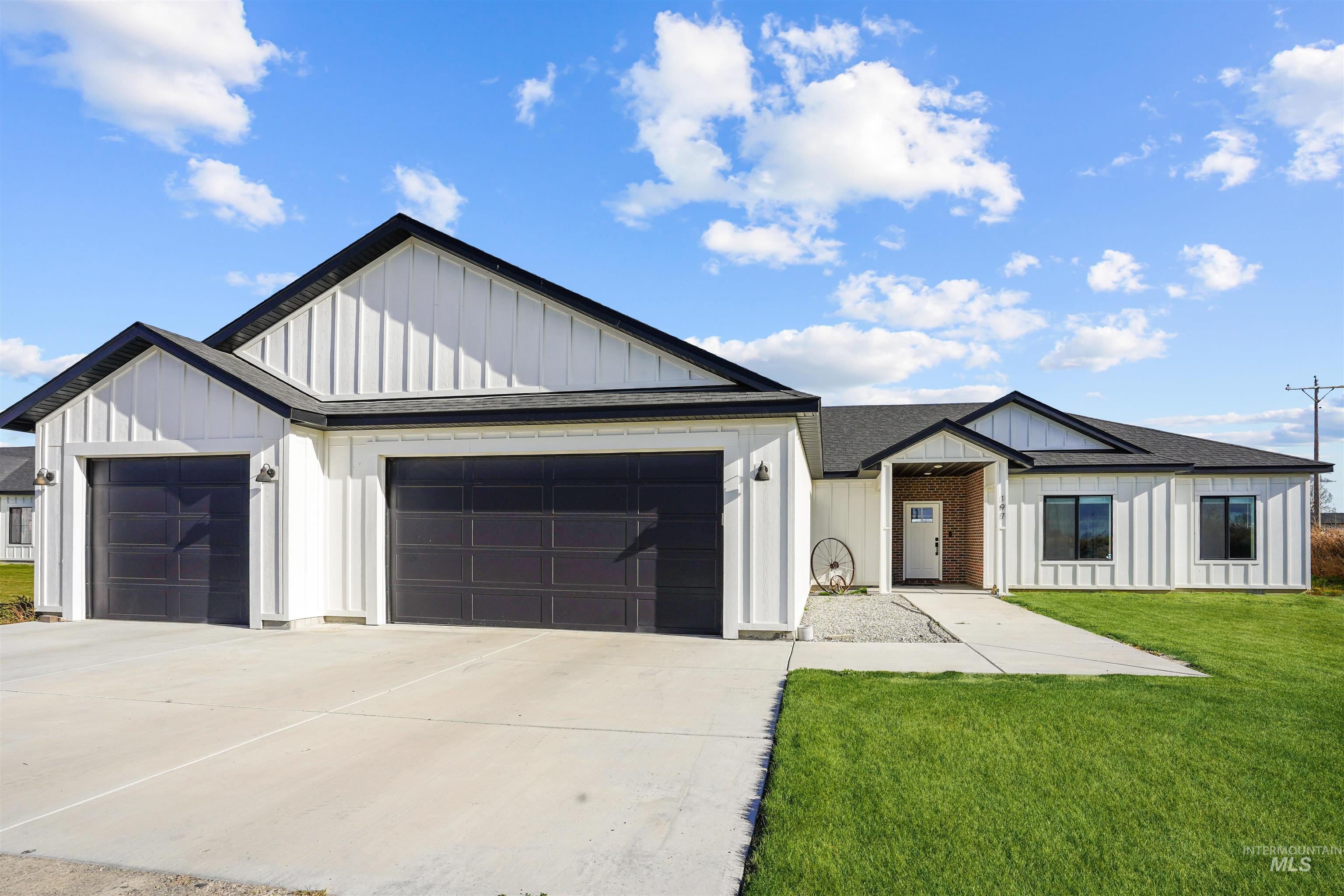 Modern farmhouse style home featuring board and batten siding, a shingled roof, a front yard, and concrete driveway