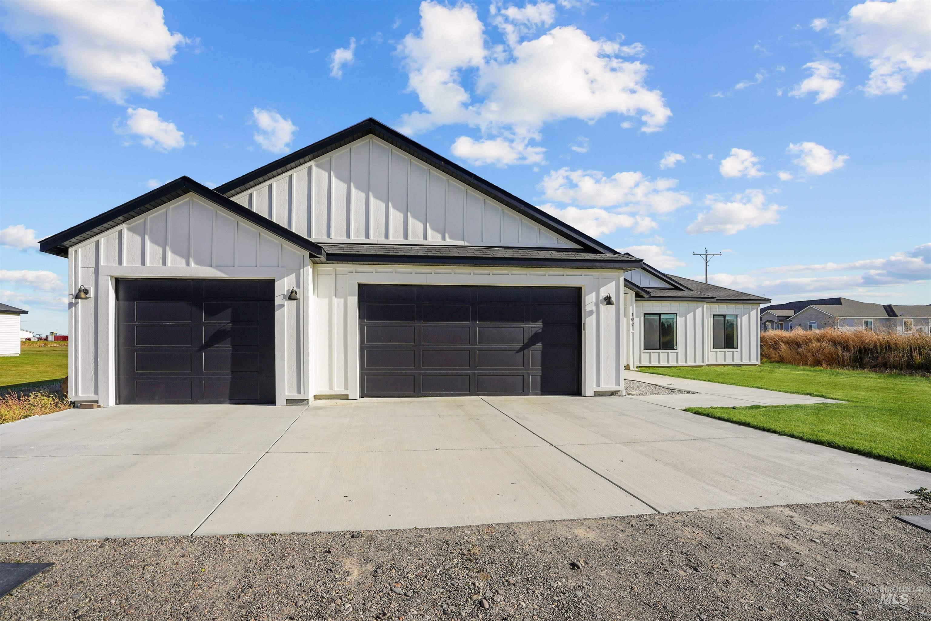 View of front of property featuring board and batten siding, a garage, concrete driveway, and a front yard