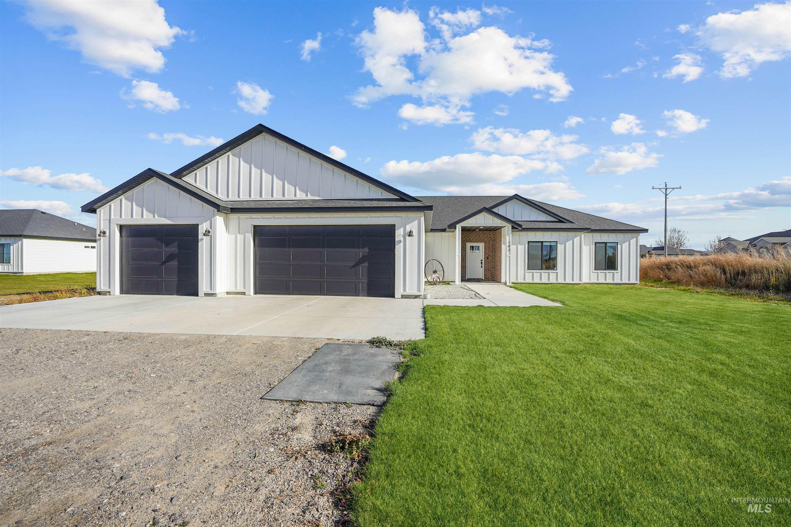 Modern farmhouse style home with driveway, board and batten siding, a front yard, and a garage
