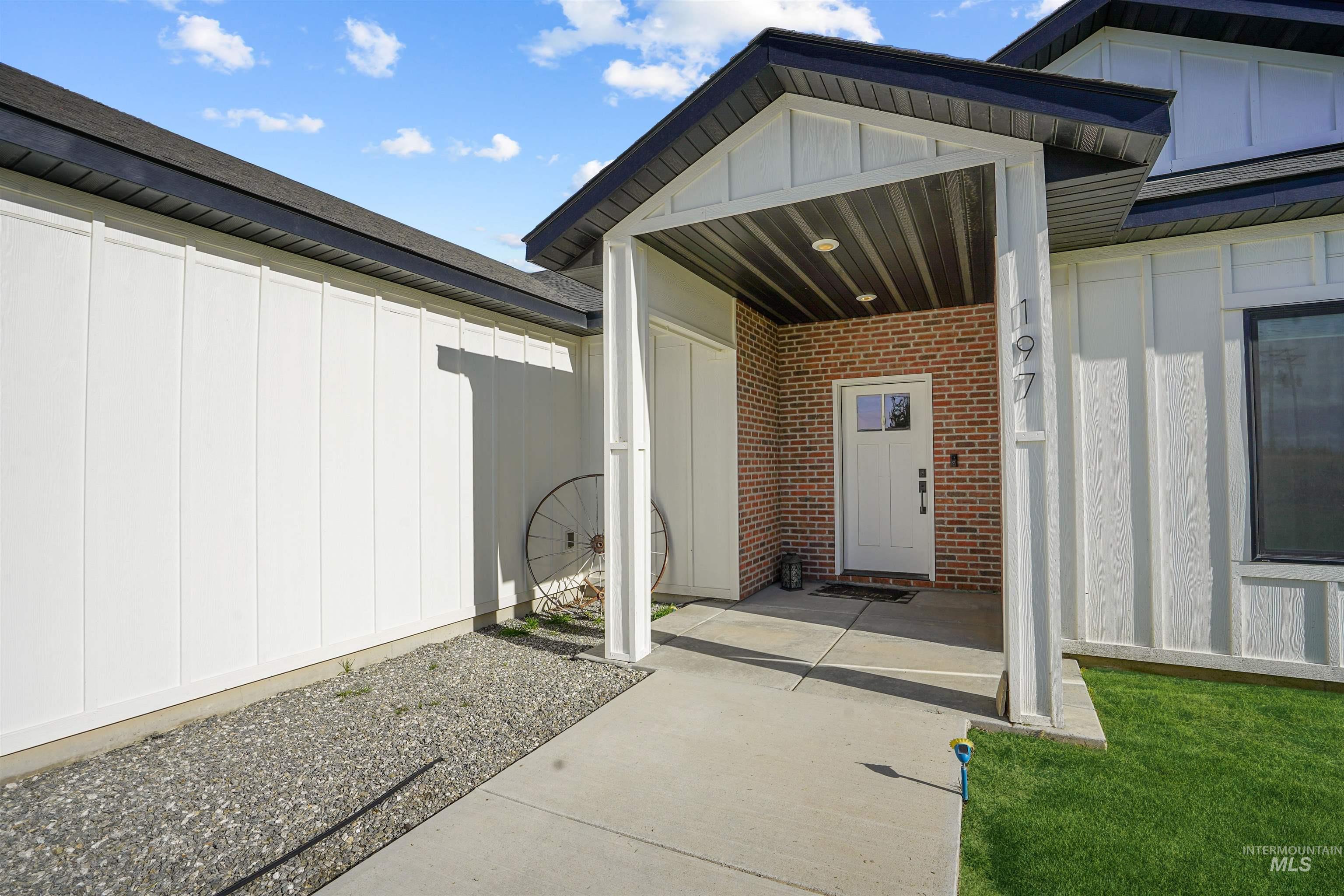 Doorway to property with board and batten siding and brick siding