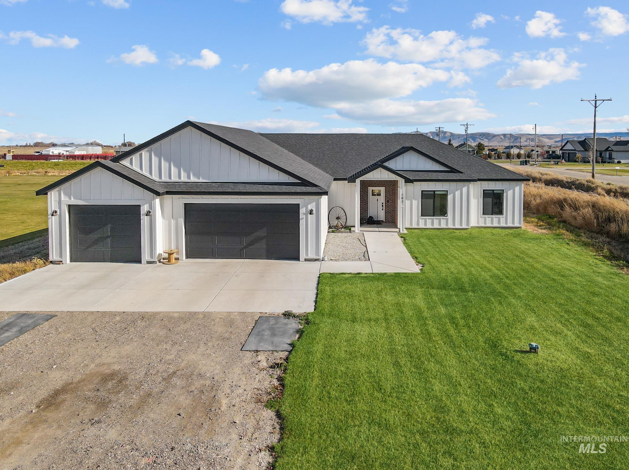 Modern inspired farmhouse featuring concrete driveway, a front yard, roof with shingles, and a garage
