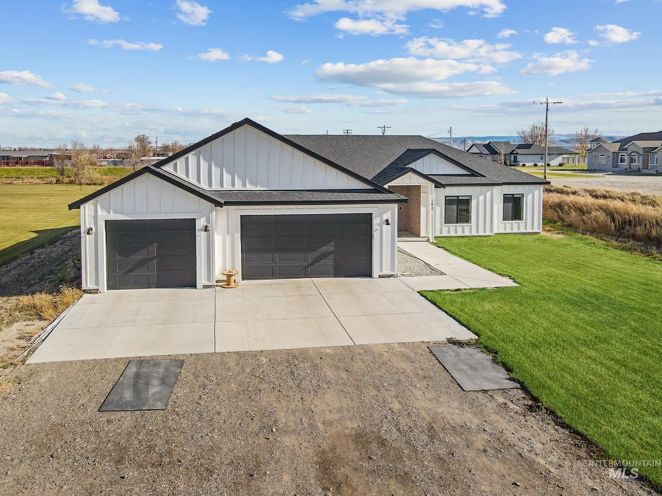 Modern inspired farmhouse with concrete driveway, a front lawn, roof with shingles, and board and batten siding
