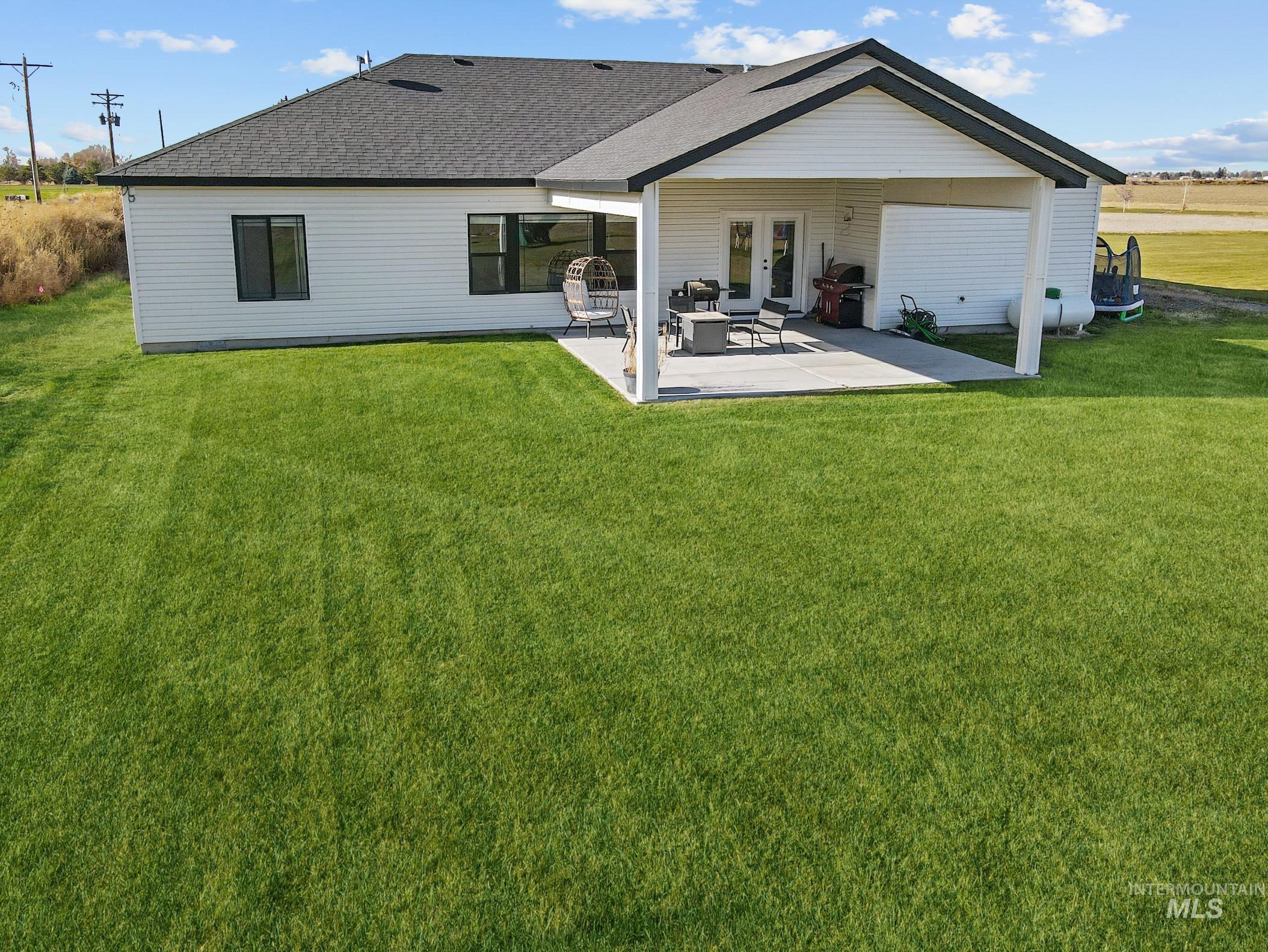 Rear view of house featuring a shingled roof, a yard, a patio, and french doors