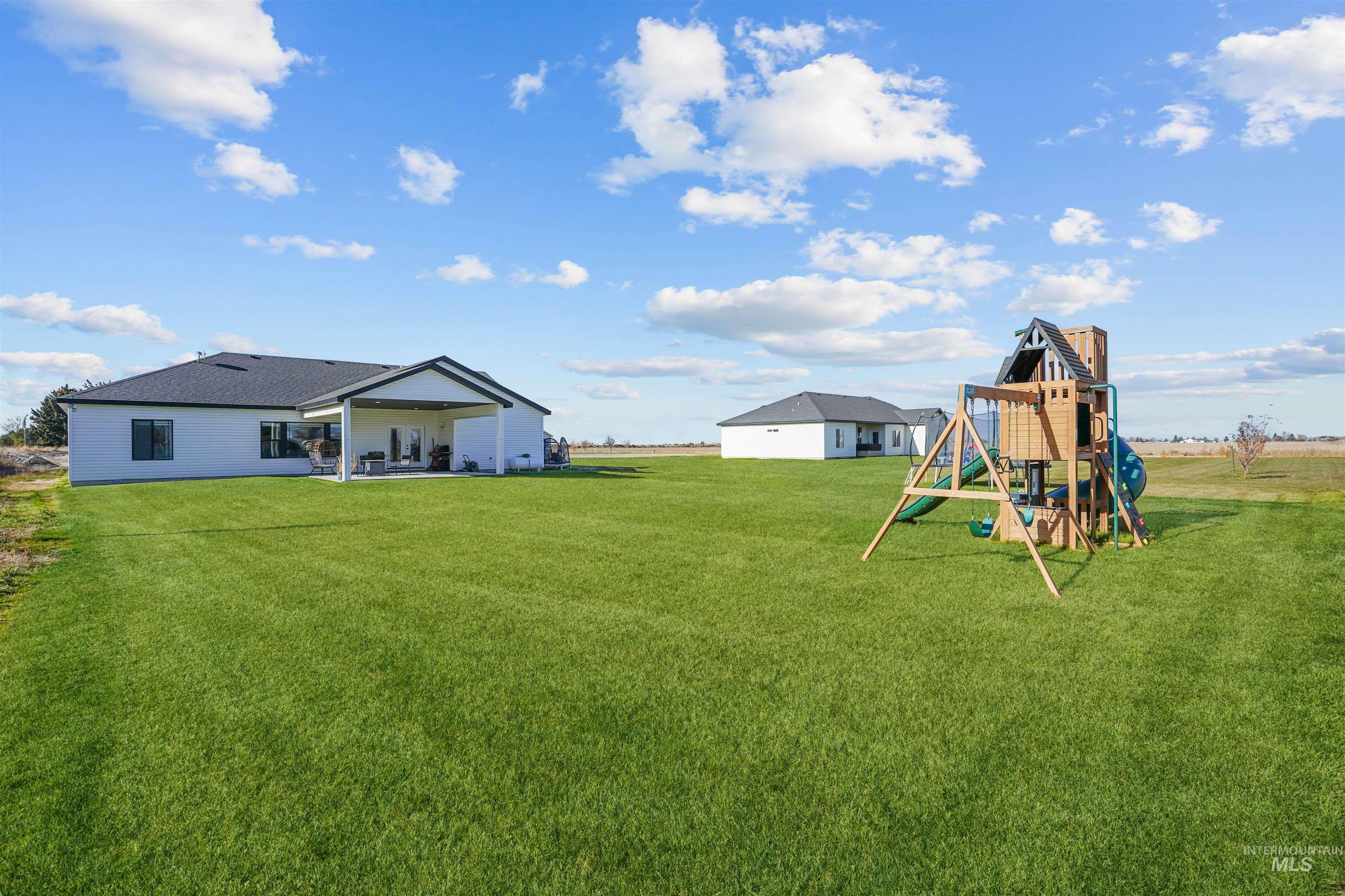 View of green lawn with a patio area and a playground