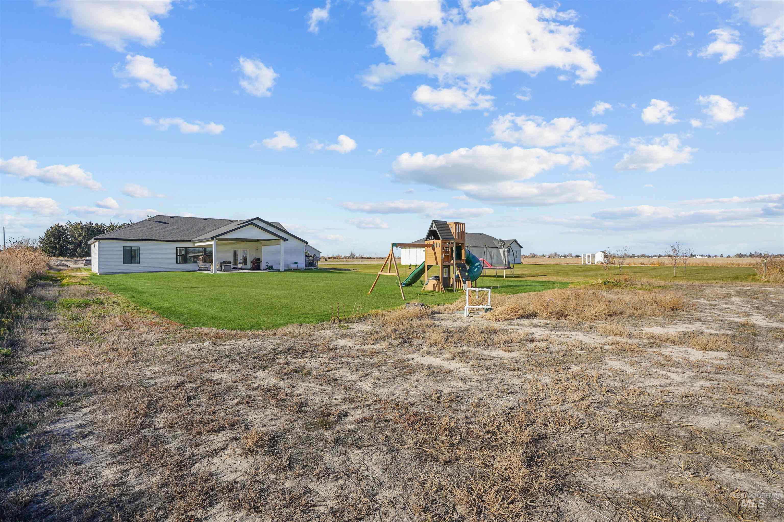 View of grassy yard featuring a playground and a patio