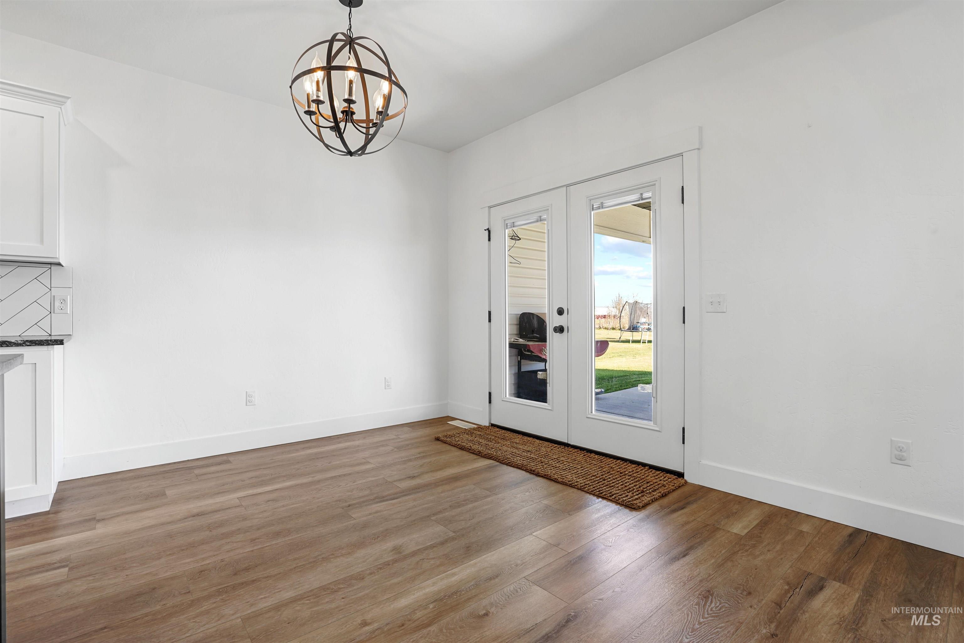 Unfurnished dining area with dark wood-type flooring, french doors, and a chandelier