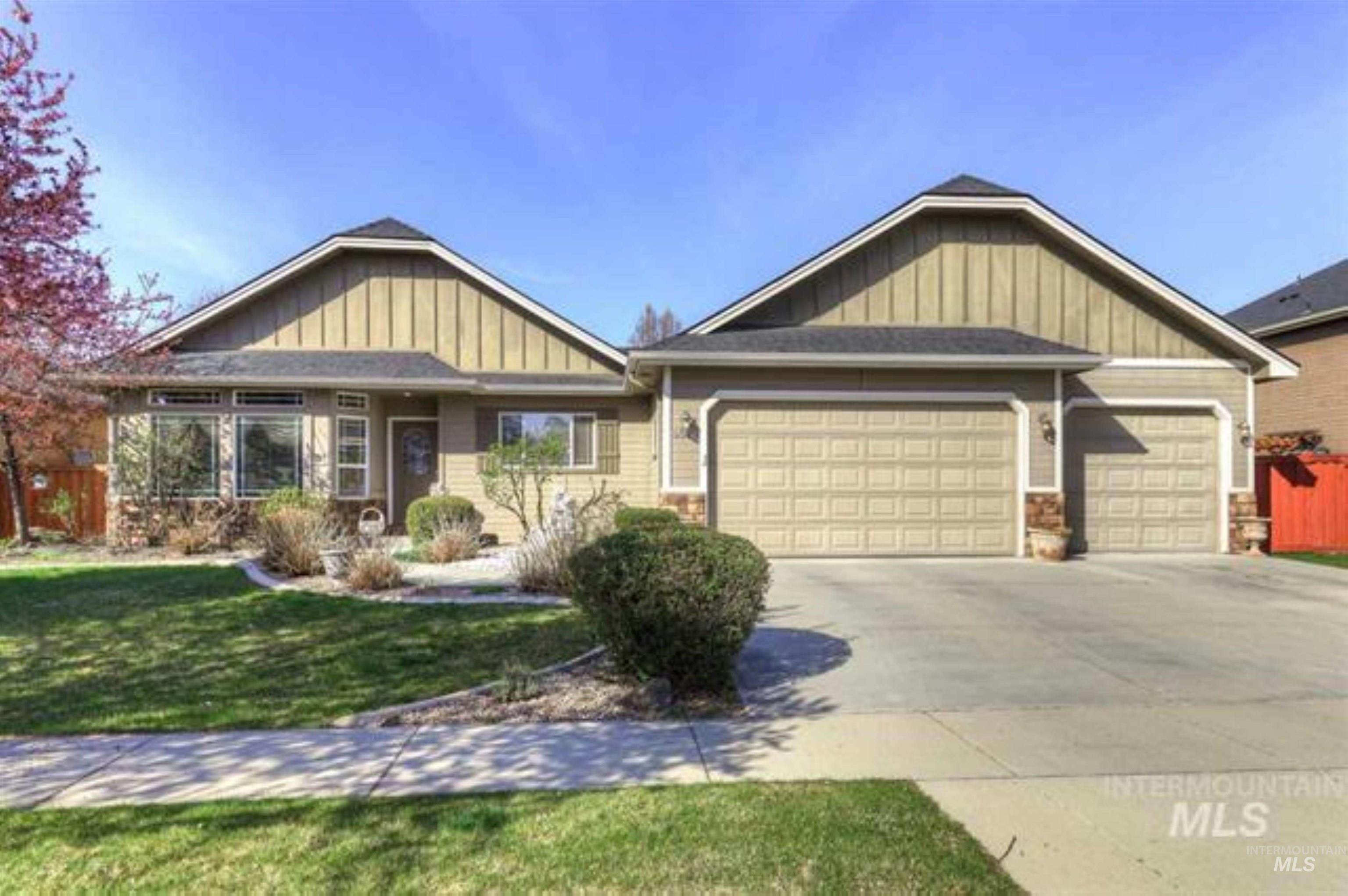 View of front of house with board and batten siding, an attached garage, concrete driveway, and stone siding