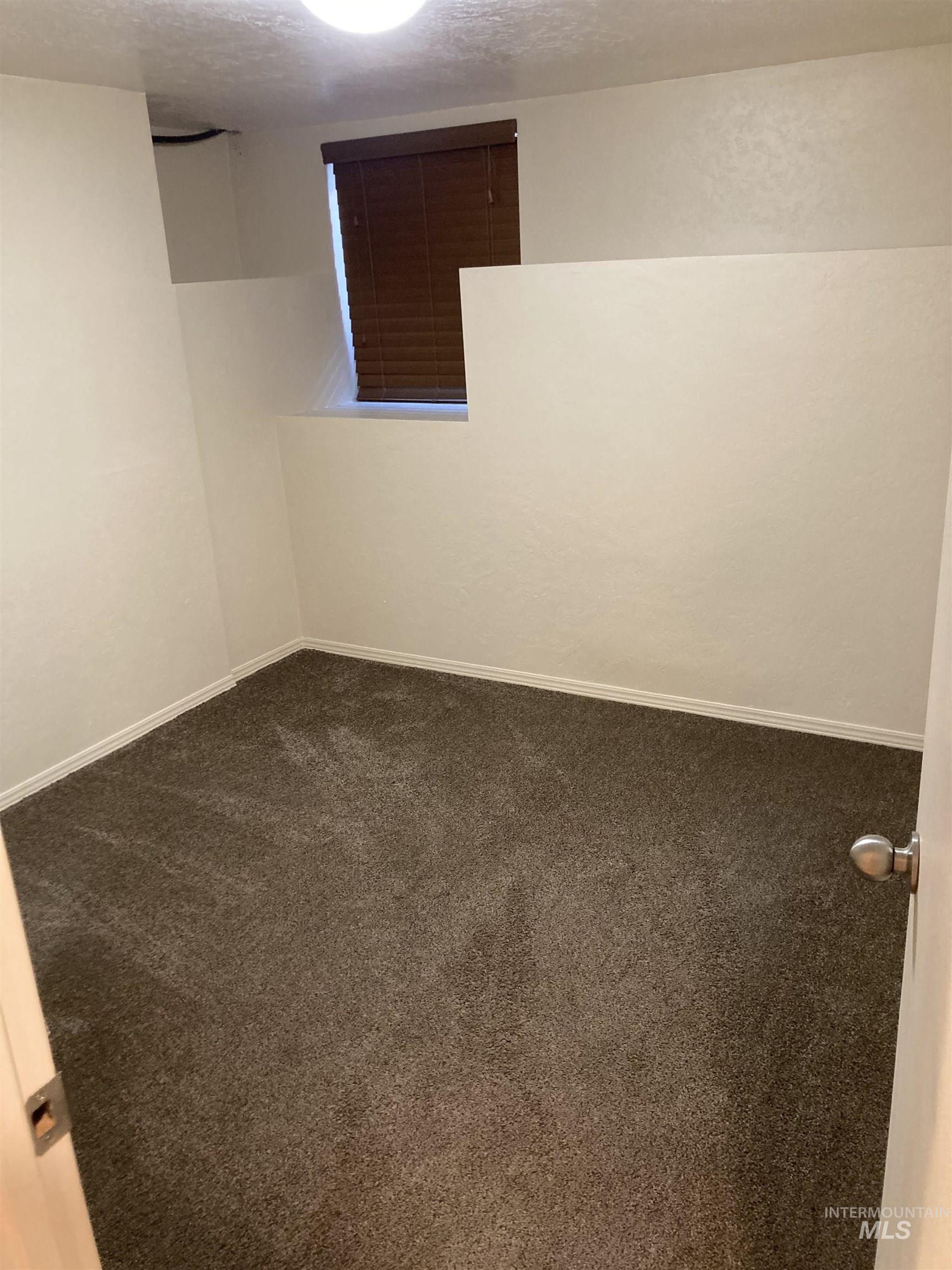 Carpeted spare room with a textured ceiling and baseboards