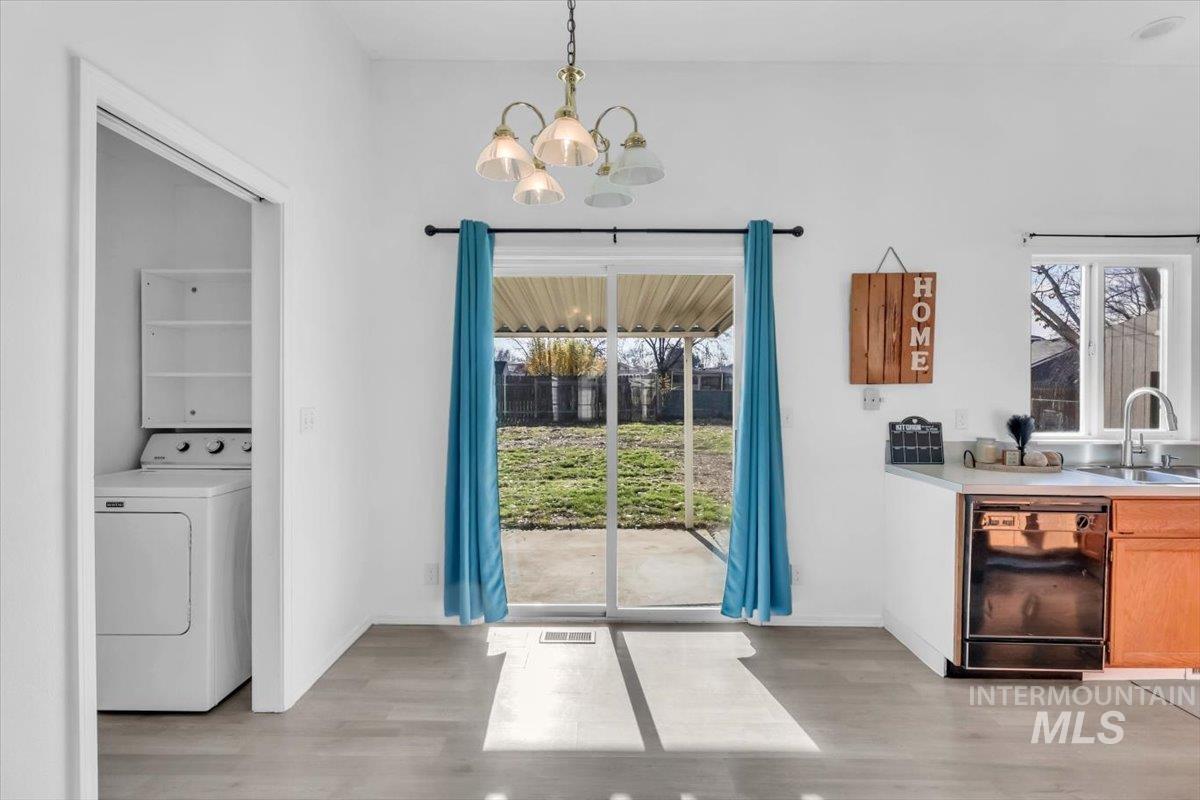 Dining space featuring washer / clothes dryer, light wood finished floors, and a chandelier