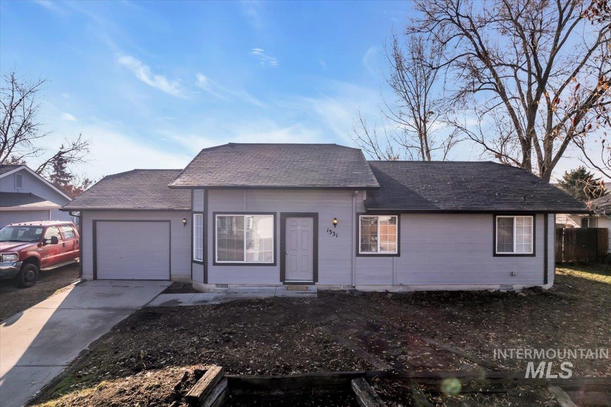 View of front of property featuring a shingled roof, driveway, and an attached garage