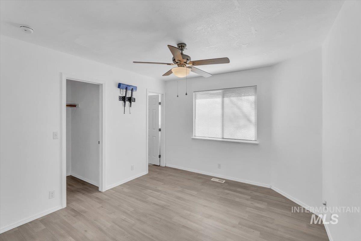 Unfurnished bedroom with light wood-style flooring, ceiling fan, and a spacious closet