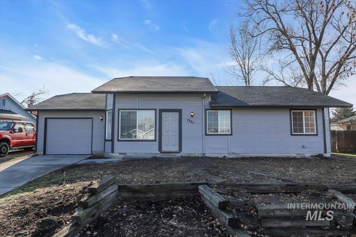 View of front of property with a garage, concrete driveway, and a shingled roof