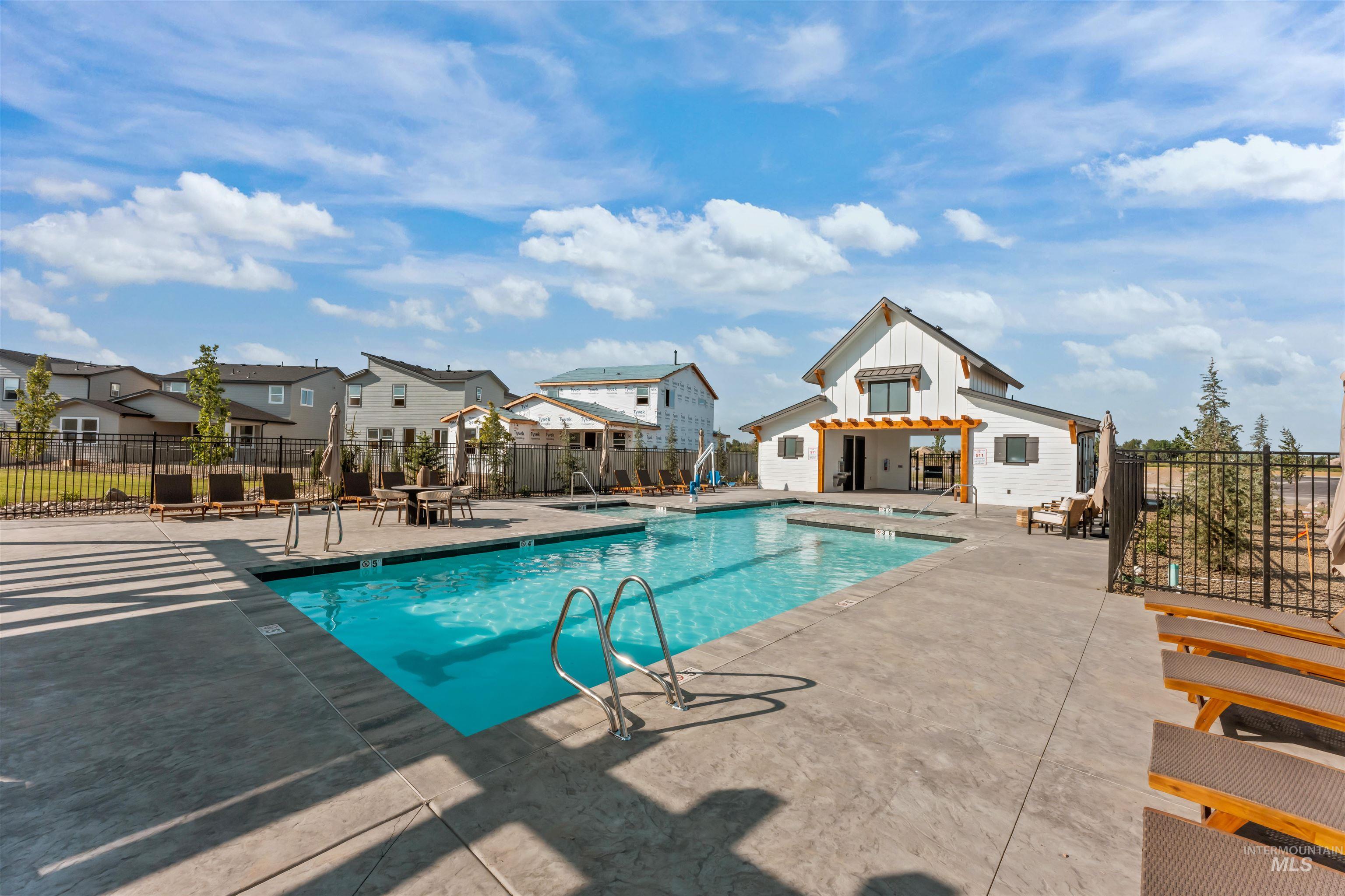 Community pool with a patio area, a hot tub, and a residential view
