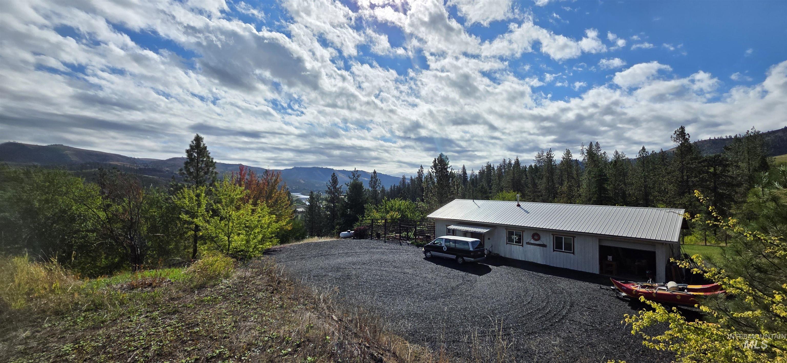 View of front facade featuring a metal roof, a mountain view, and a view of trees