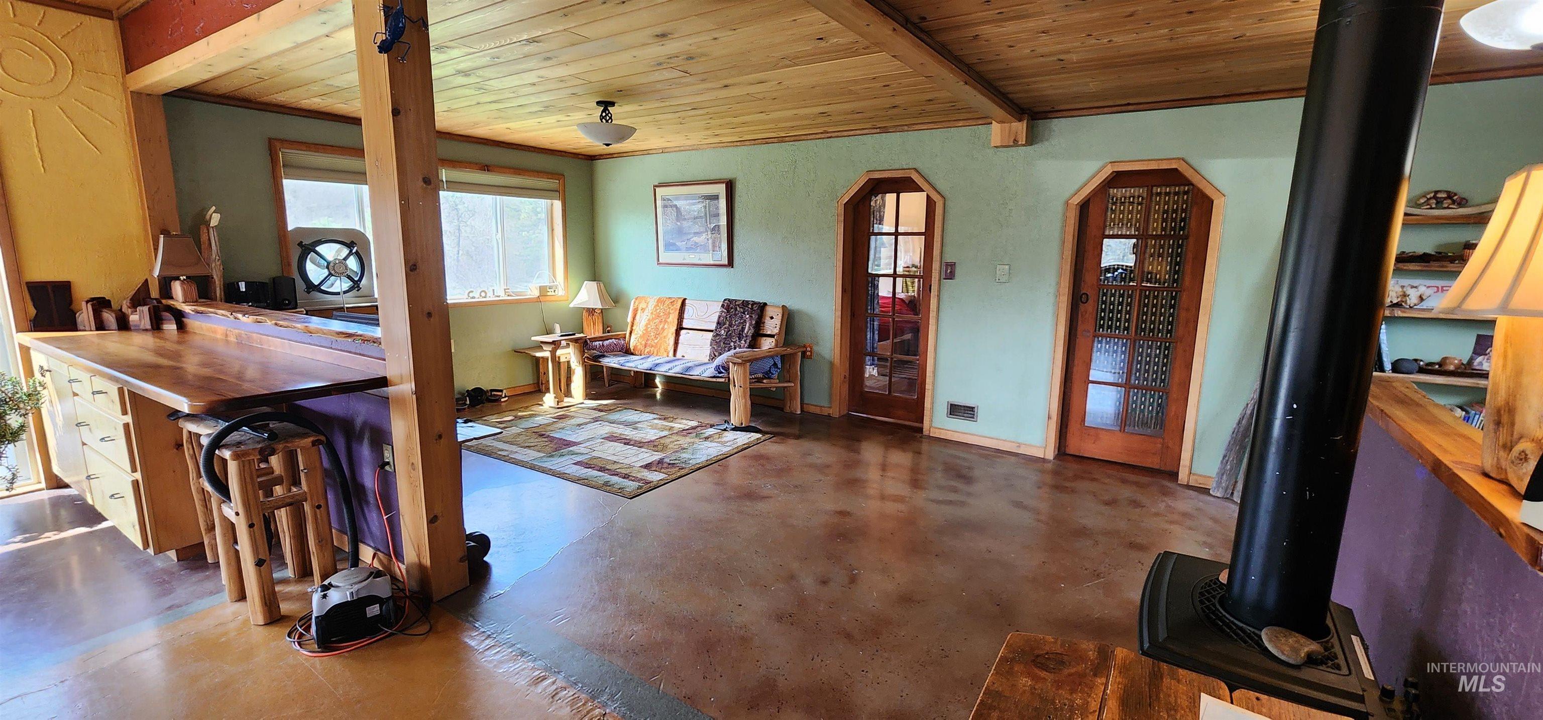 Living area with finished concrete flooring, a wood ceiling with exposed beams, and arched walkways