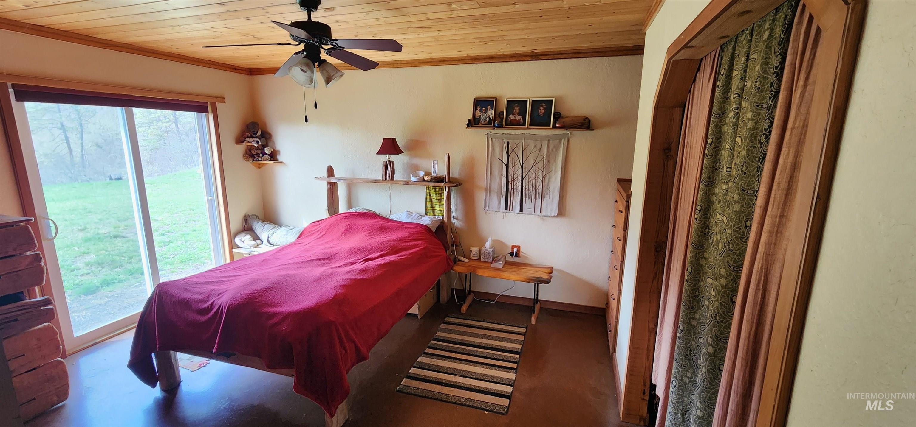 Bedroom featuring wooden ceiling, access to outside, finished concrete flooring, crown molding, and ceiling fan