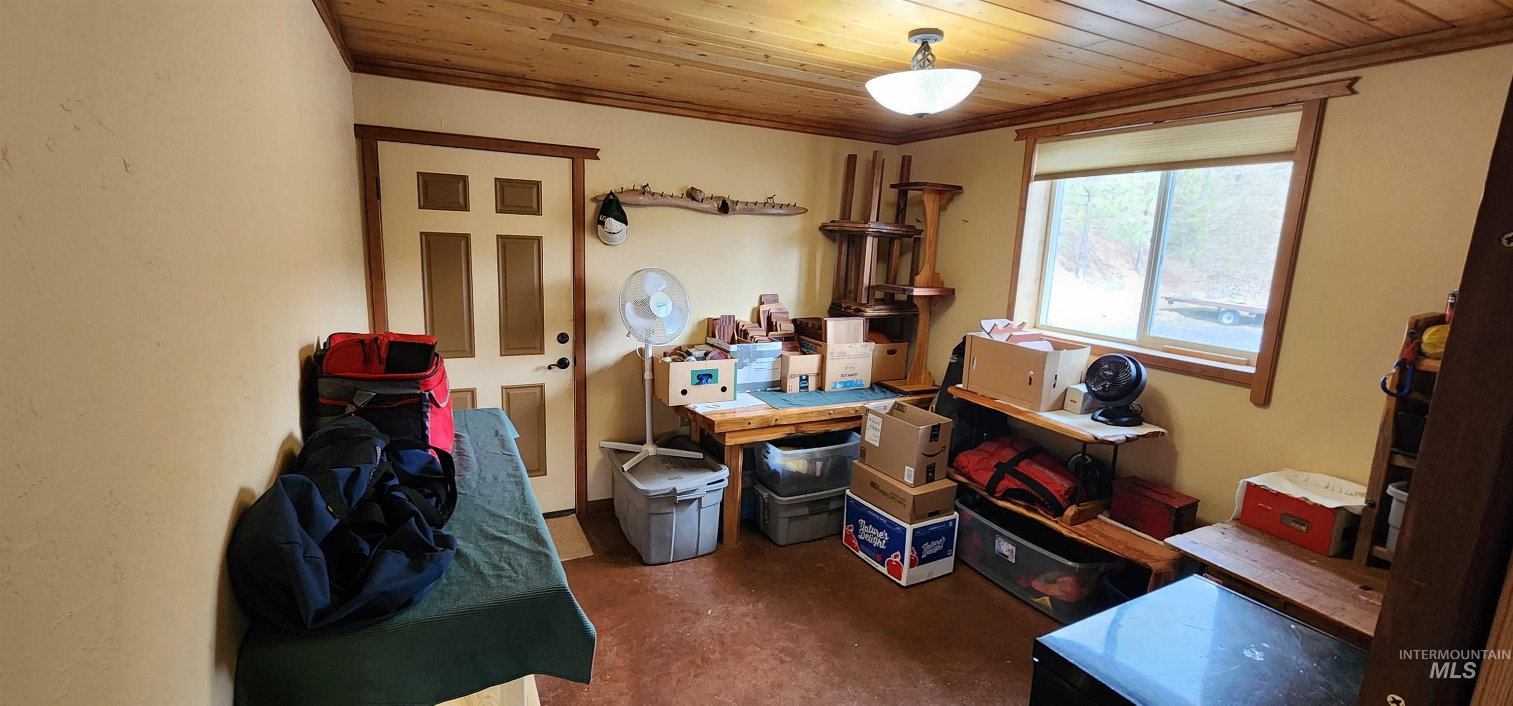 Office featuring wood ceiling, finished concrete flooring, and crown molding