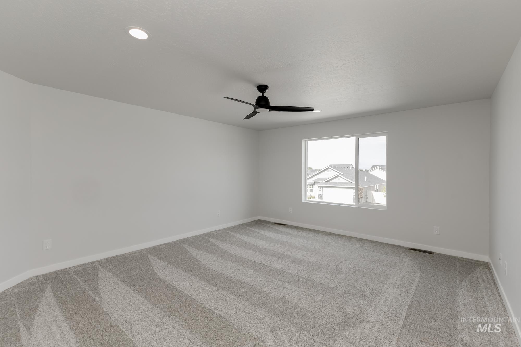 Empty room with light colored carpet and a ceiling fan