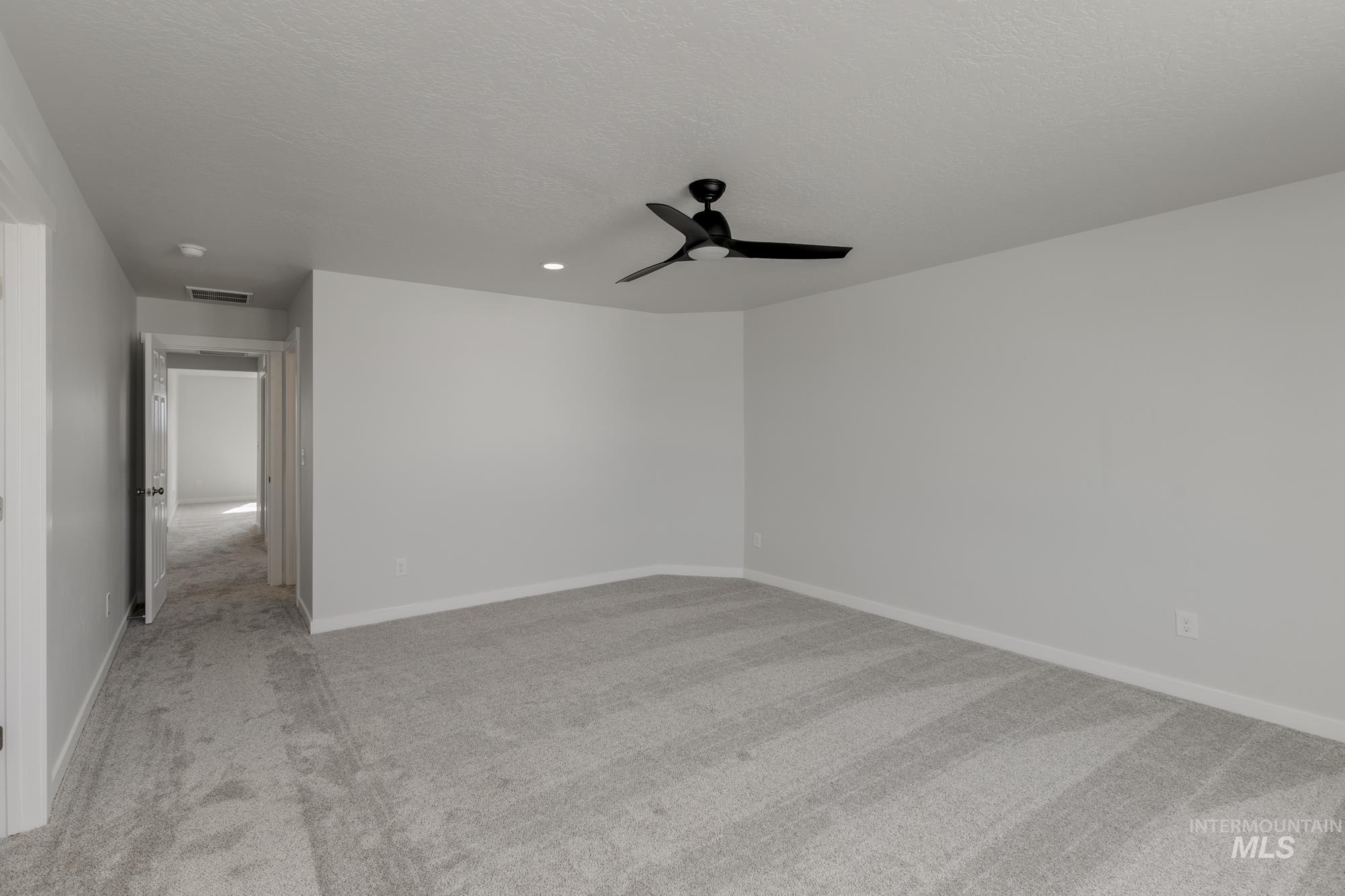 Empty room featuring light carpet, ceiling fan, a textured ceiling, and recessed lighting
