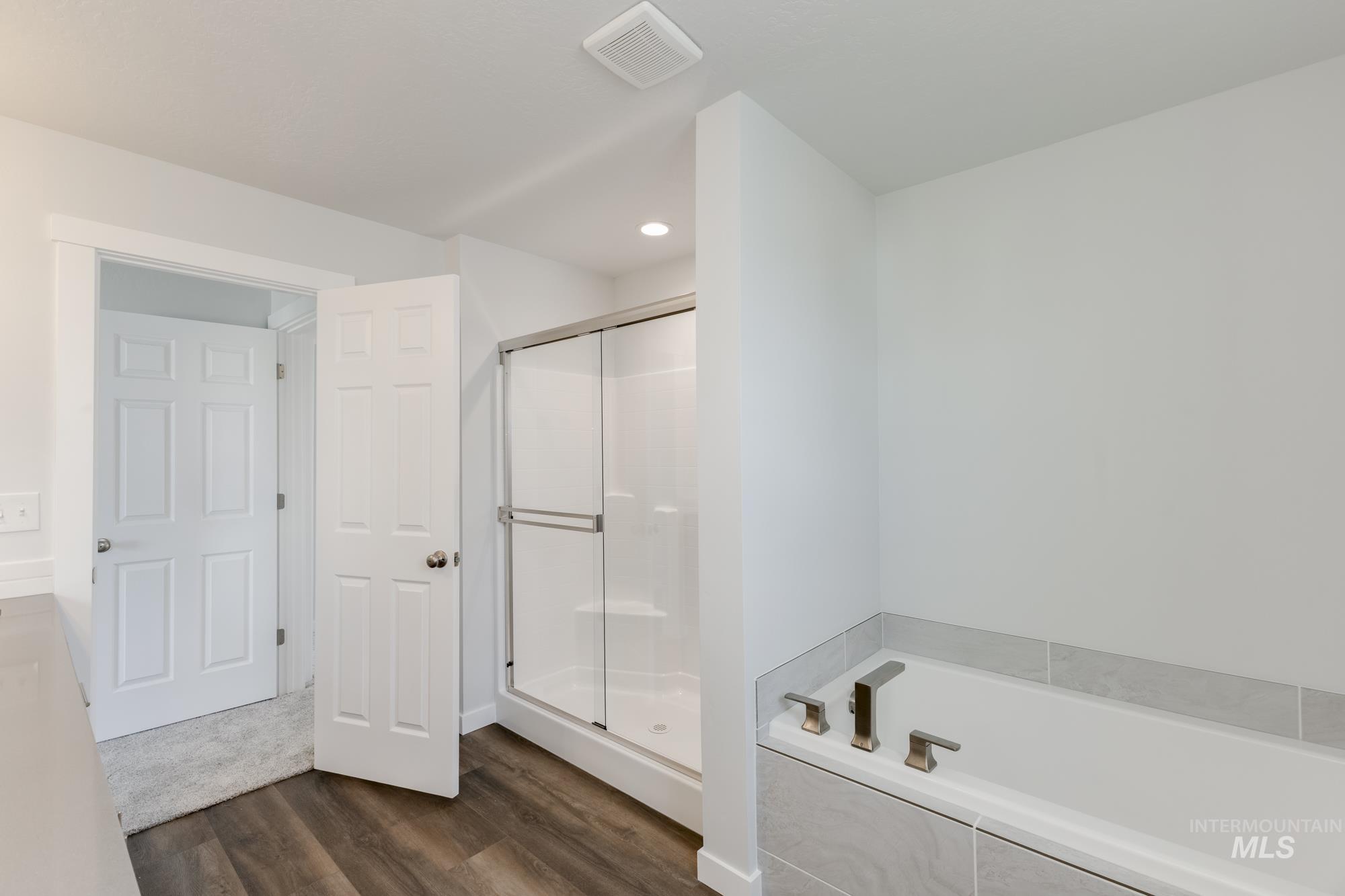 Full bathroom featuring a stall shower, dark wood finished floors, a garden tub, and recessed lighting