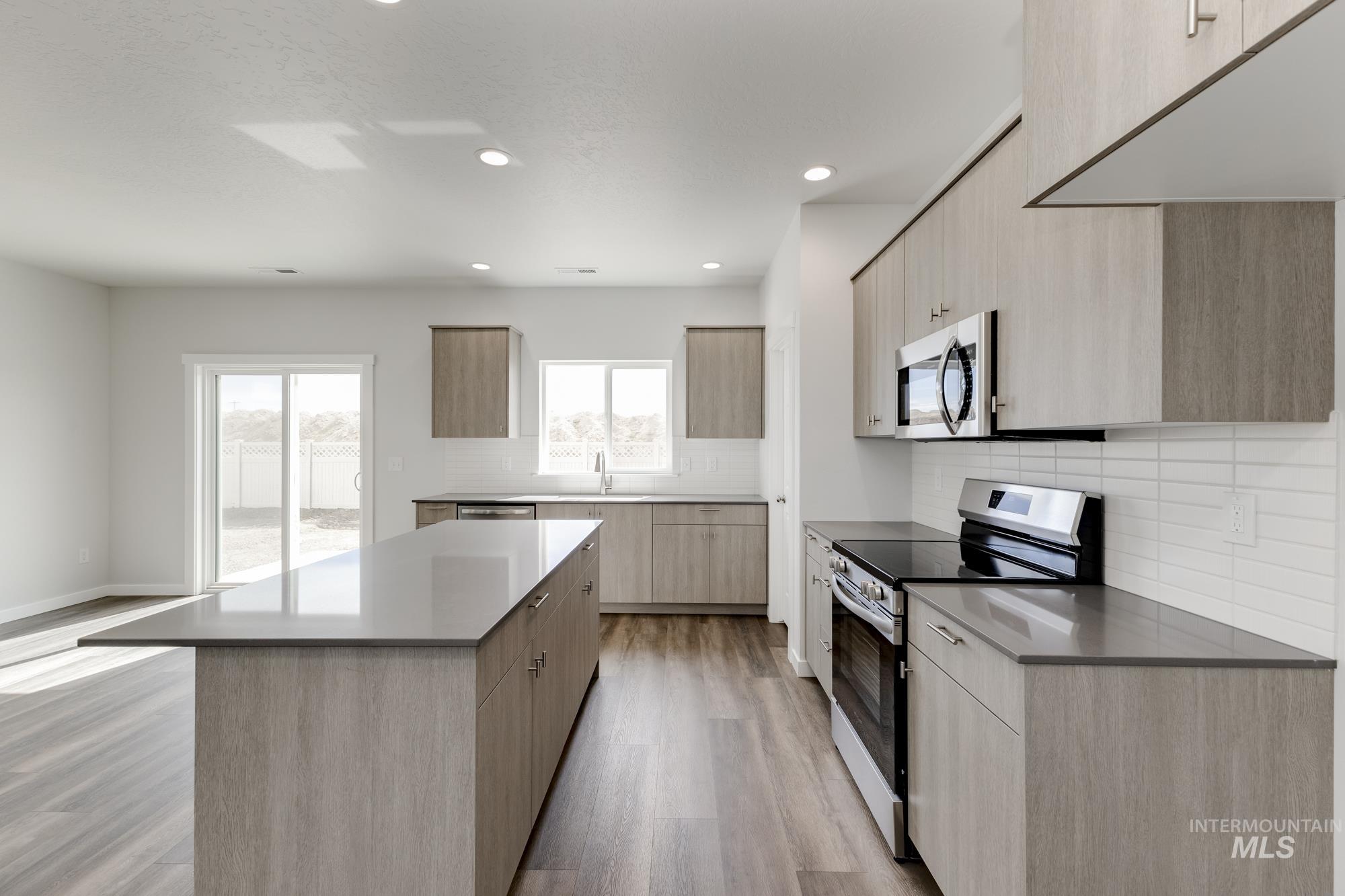 Kitchen with stainless steel appliances, light brown cabinets, modern cabinets, decorative backsplash, and recessed lighting