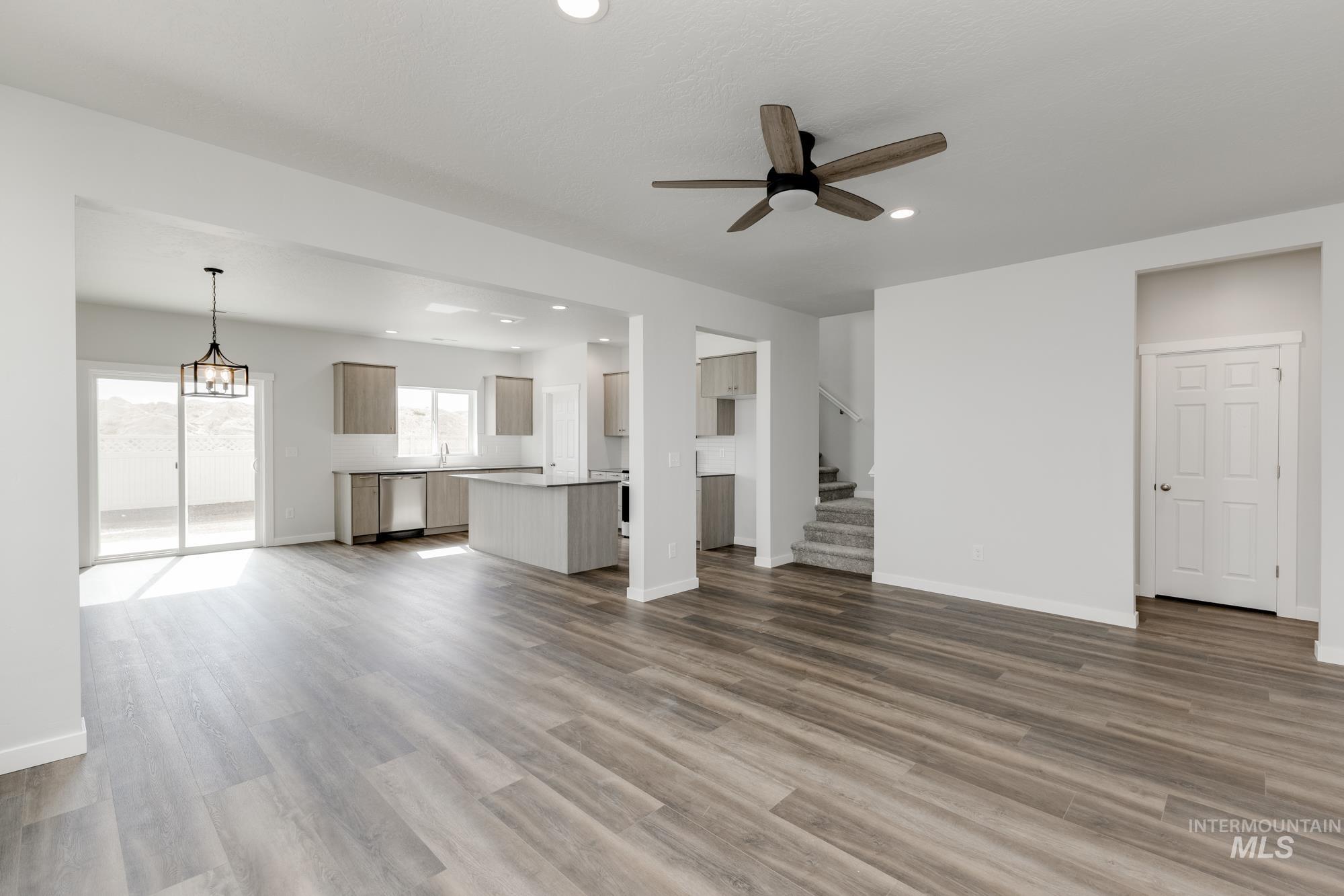 Unfurnished living room with dark wood-style floors, recessed lighting, ceiling fan, and stairway