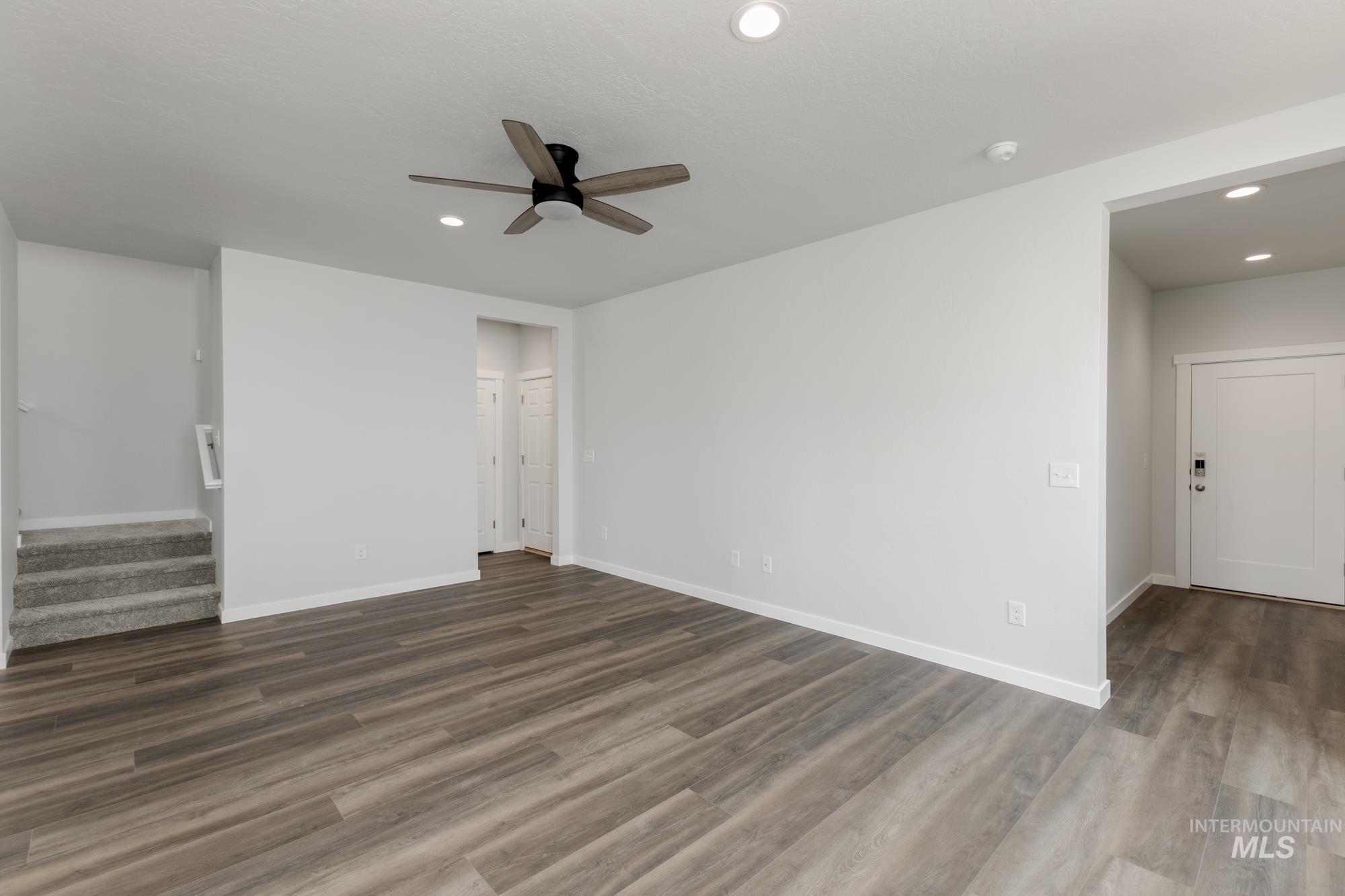 Unfurnished living room with recessed lighting, stairway, dark wood finished floors, and ceiling fan
