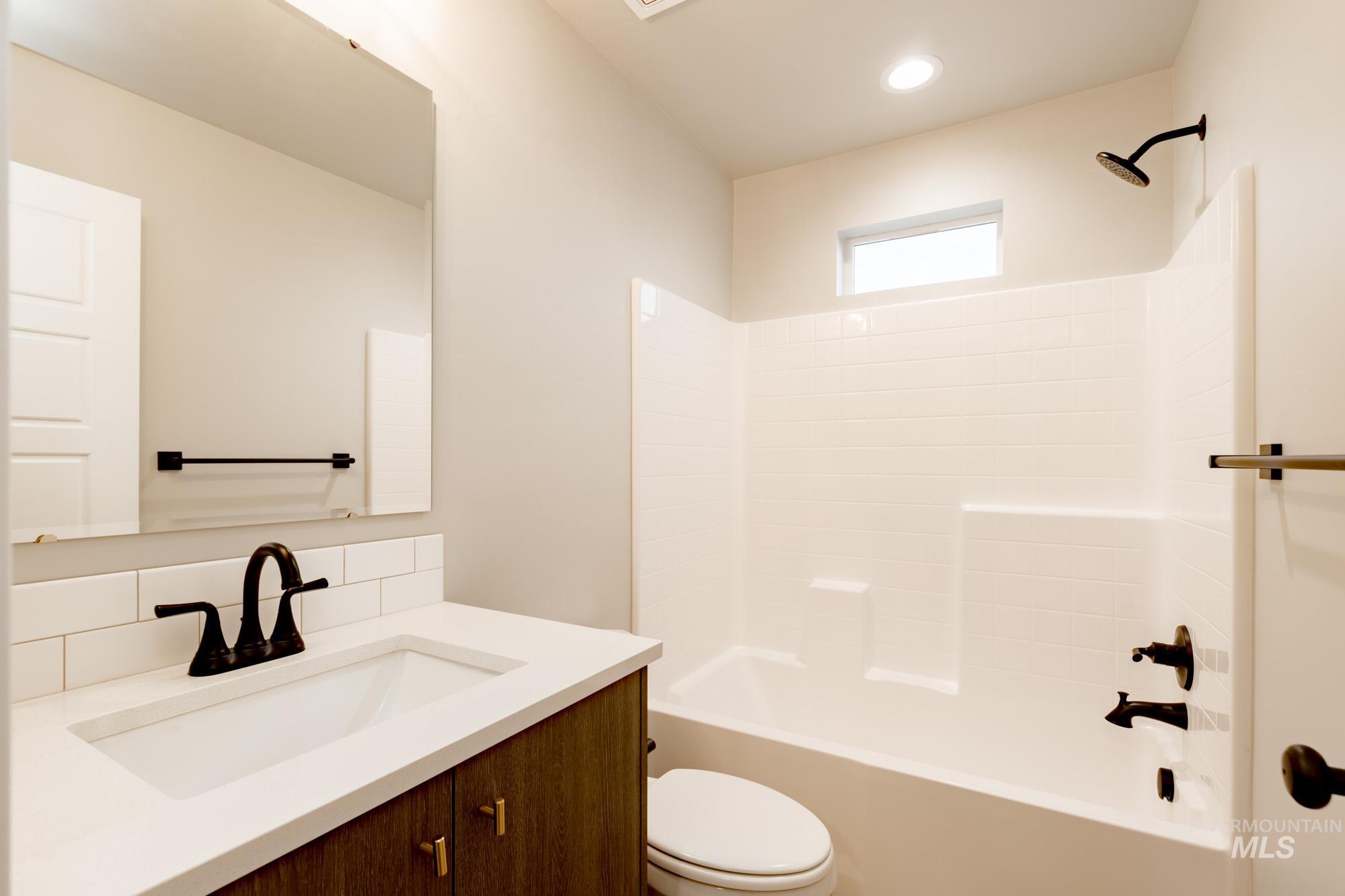 Bathroom with shower / tub combination, vanity, decorative backsplash, and recessed lighting