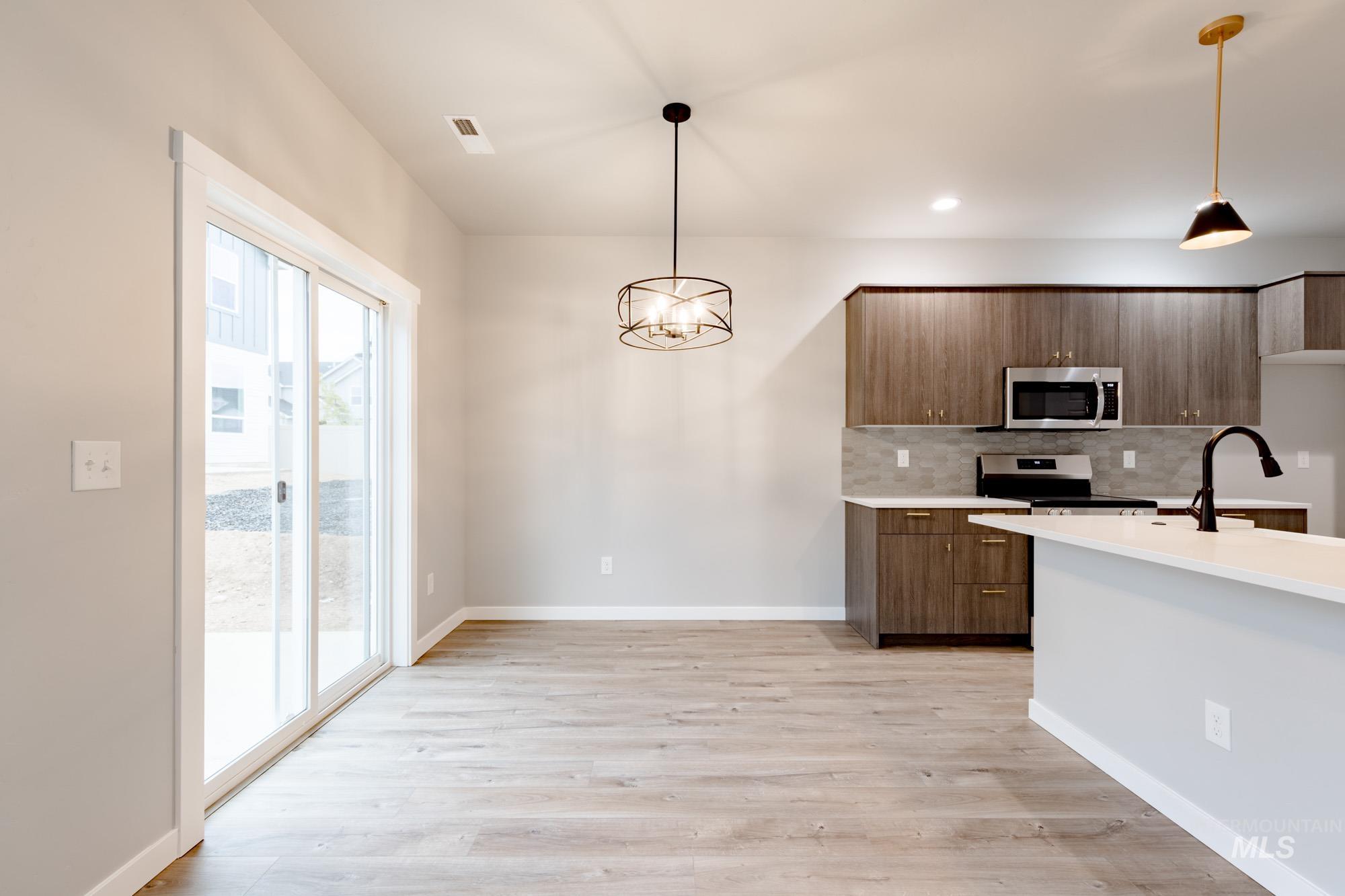 Kitchen with decorative backsplash, a chandelier, light wood-style flooring, modern cabinets, and recessed lighting