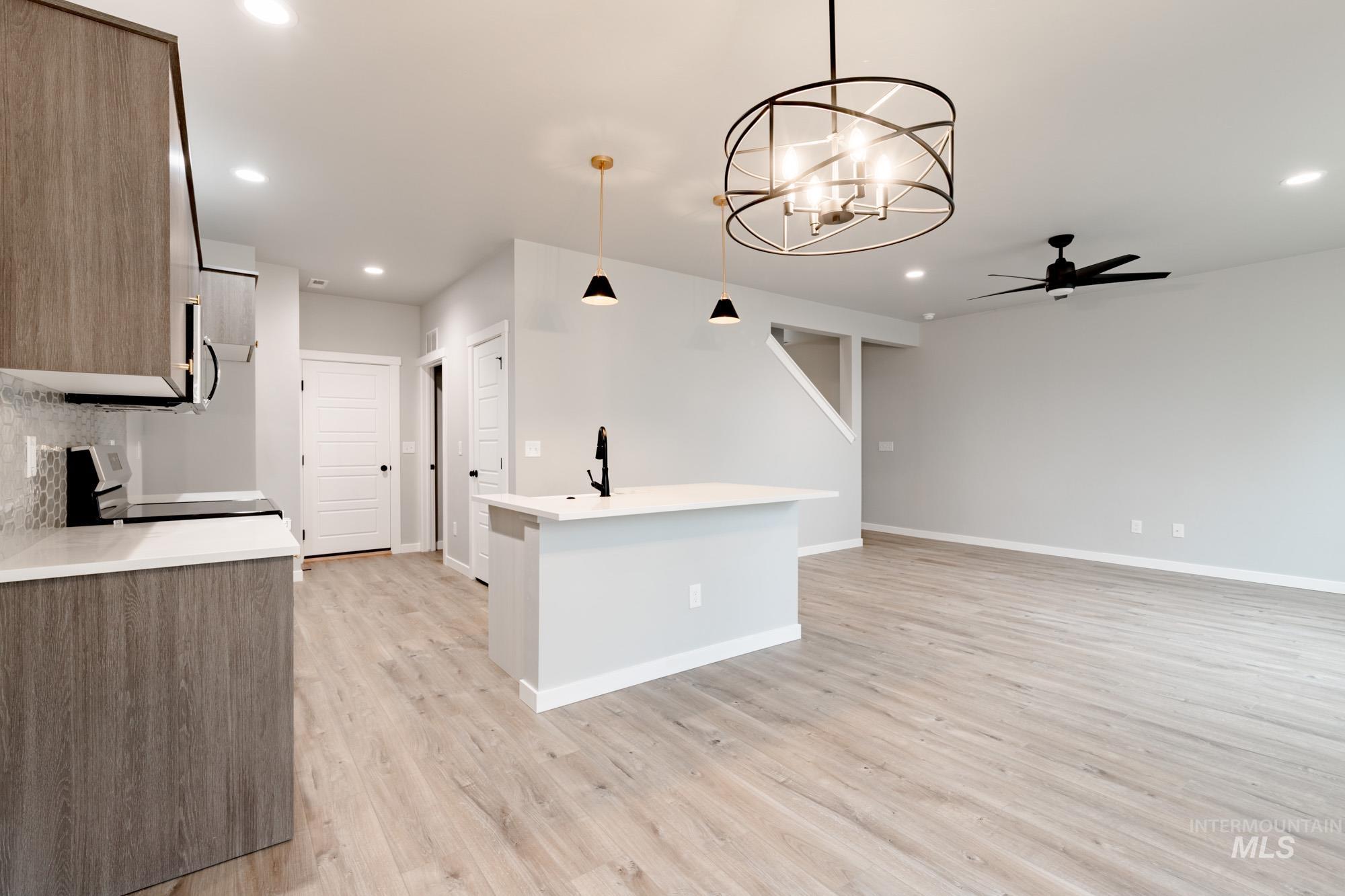 Kitchen with a ceiling fan, hanging light fixtures, a chandelier, range, and recessed lighting