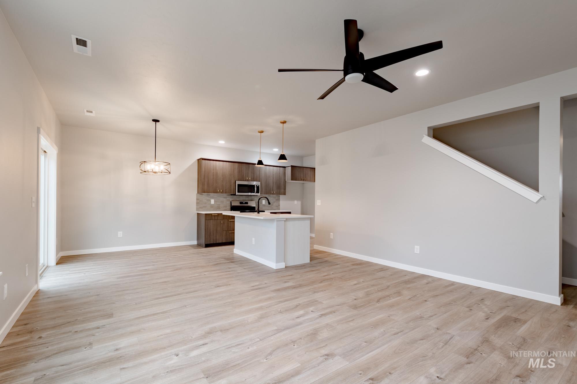 Unfurnished living room with a chandelier, light wood finished floors, recessed lighting, and a ceiling fan
