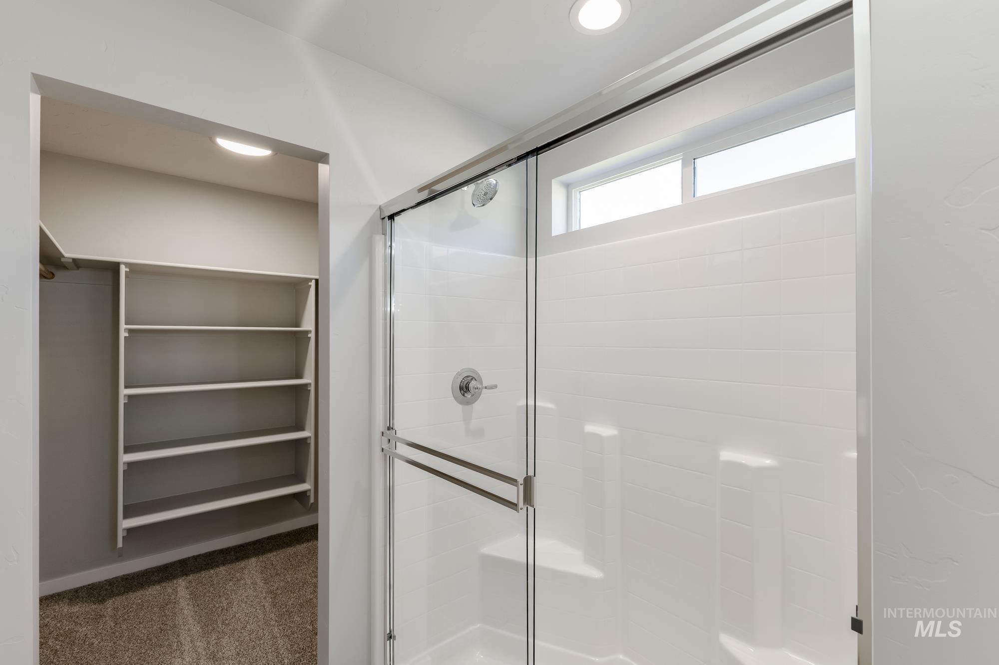 Bathroom with dark colored carpet, a stall shower, recessed lighting, and a spacious closet