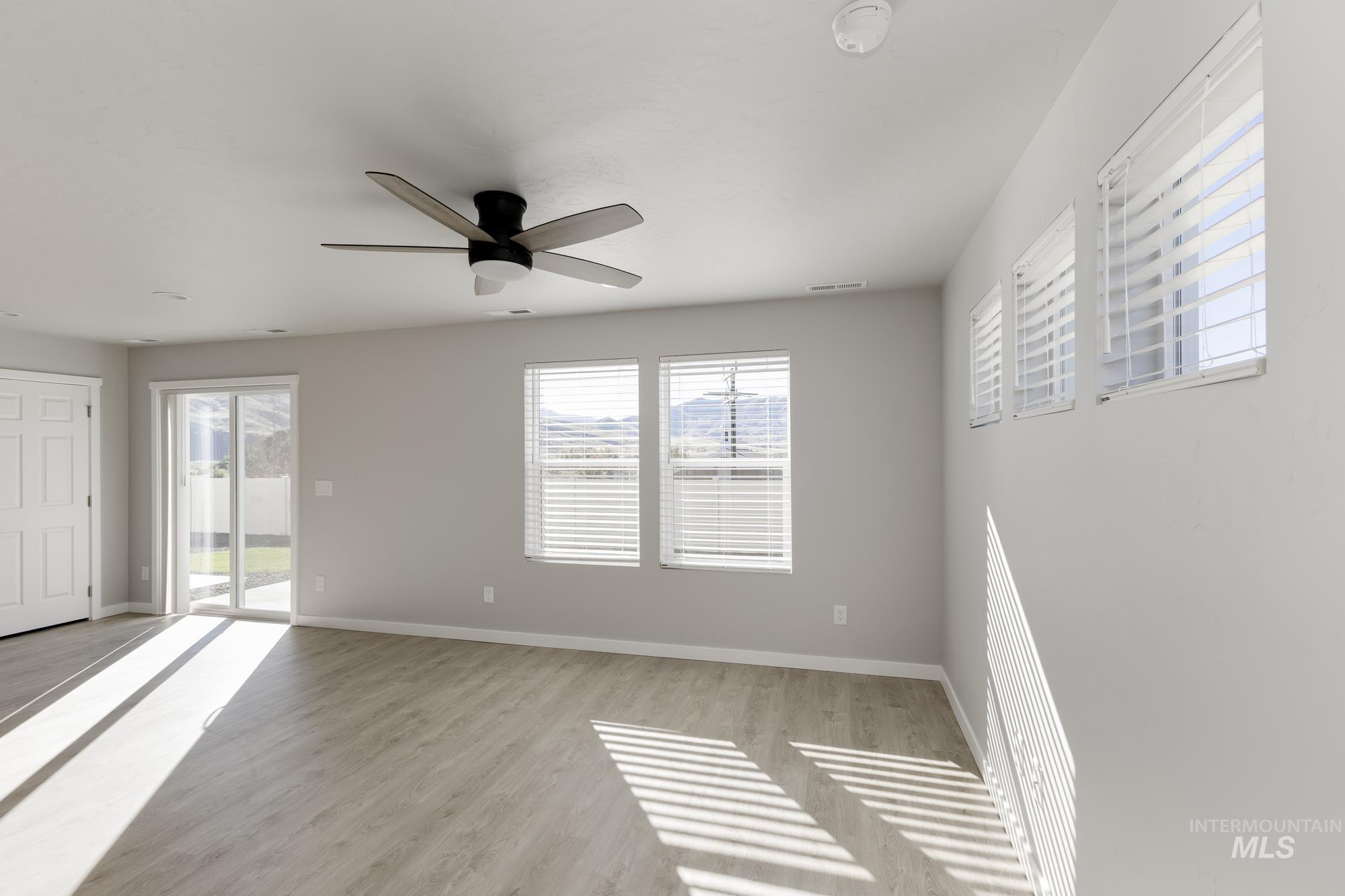 Spare room featuring healthy amount of natural light, light wood finished floors, and a ceiling fan