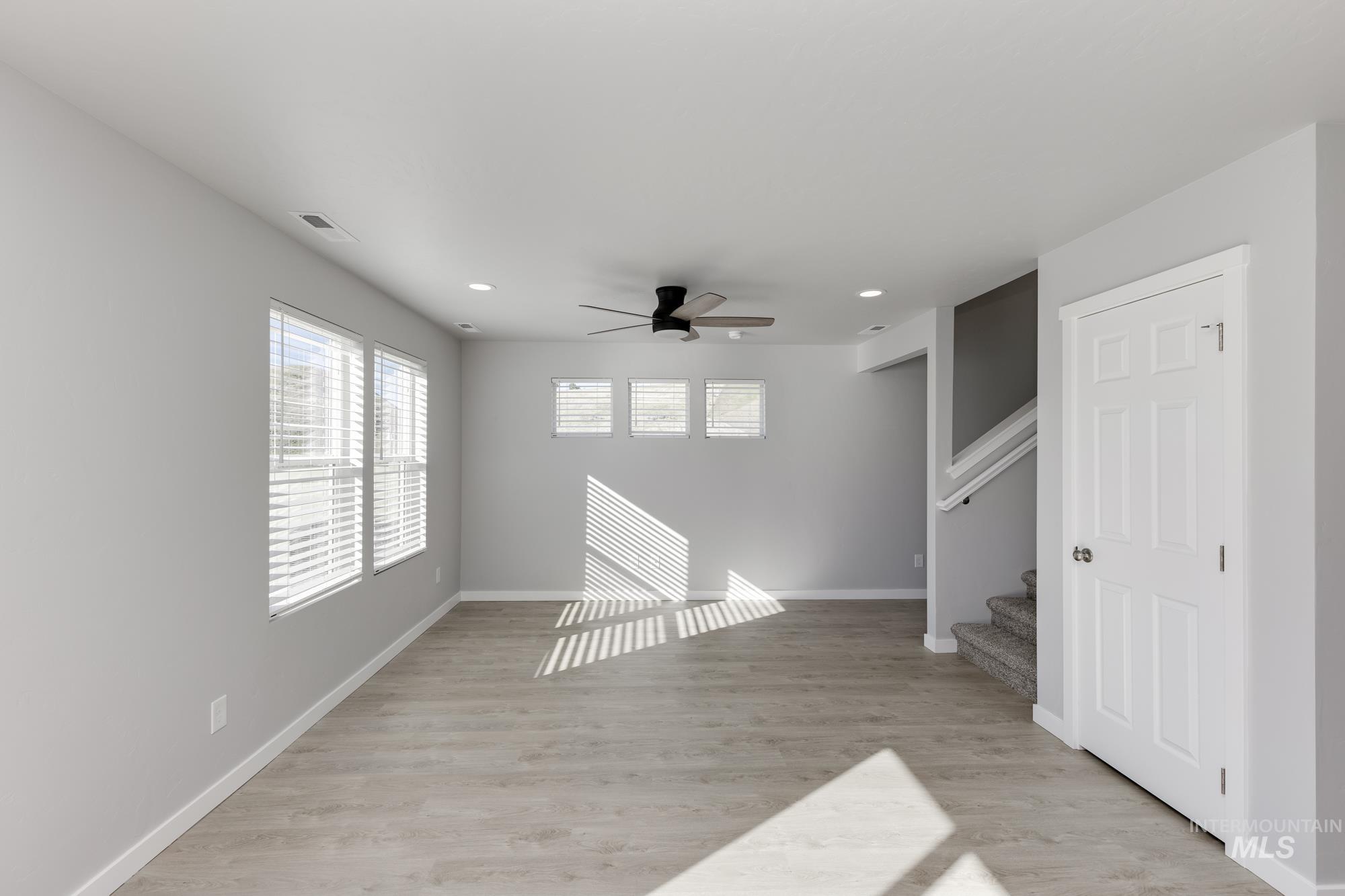 Unfurnished living room featuring light wood-style floors, ceiling fan, stairs, and recessed lighting