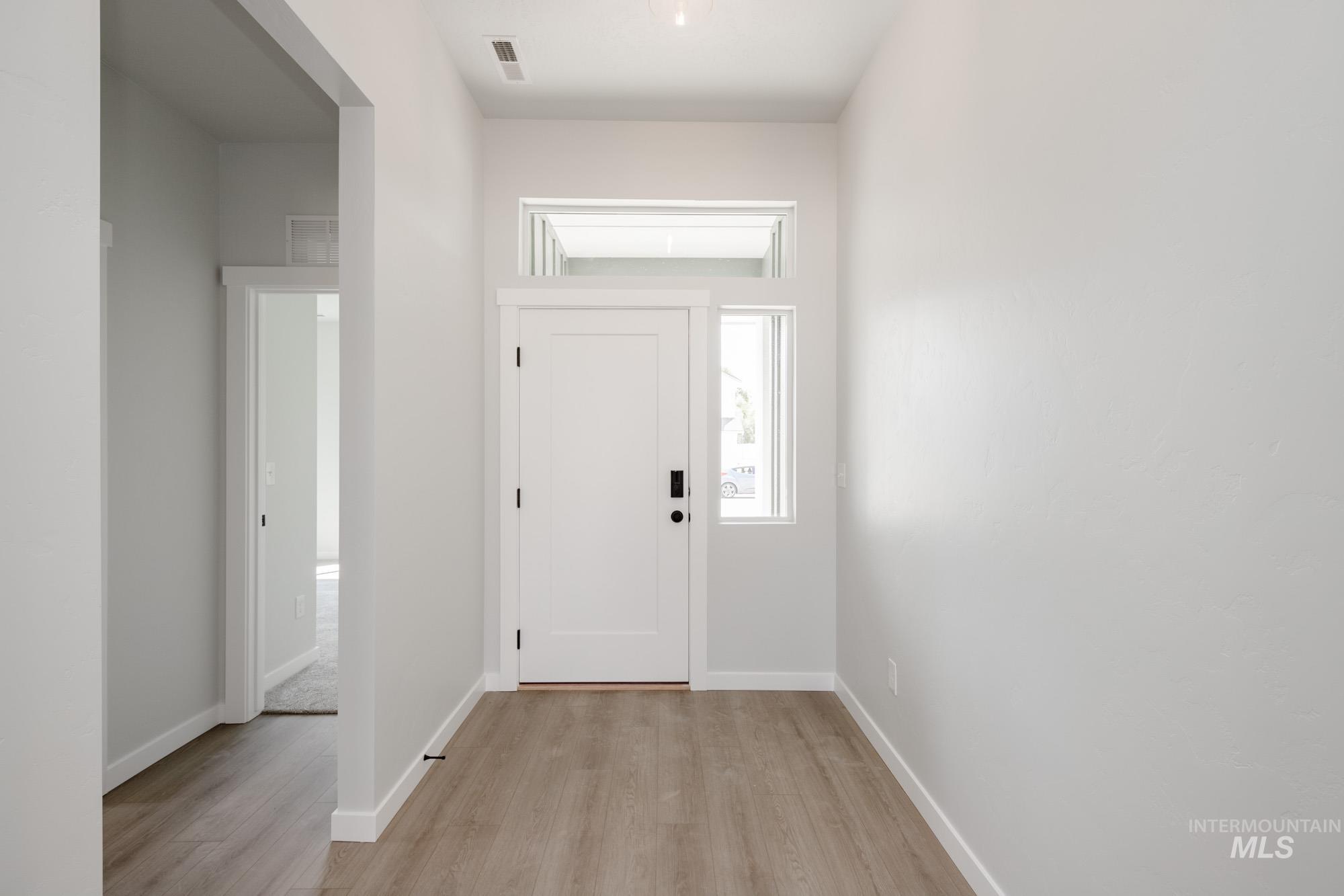 Foyer with light wood-style flooring and baseboards
