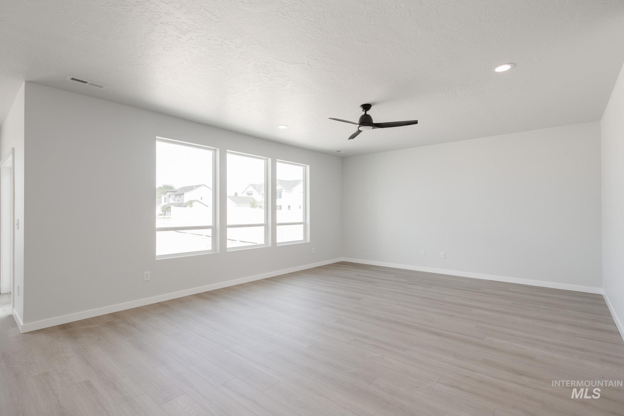 Spare room with light wood finished floors, recessed lighting, a textured ceiling, and a ceiling fan