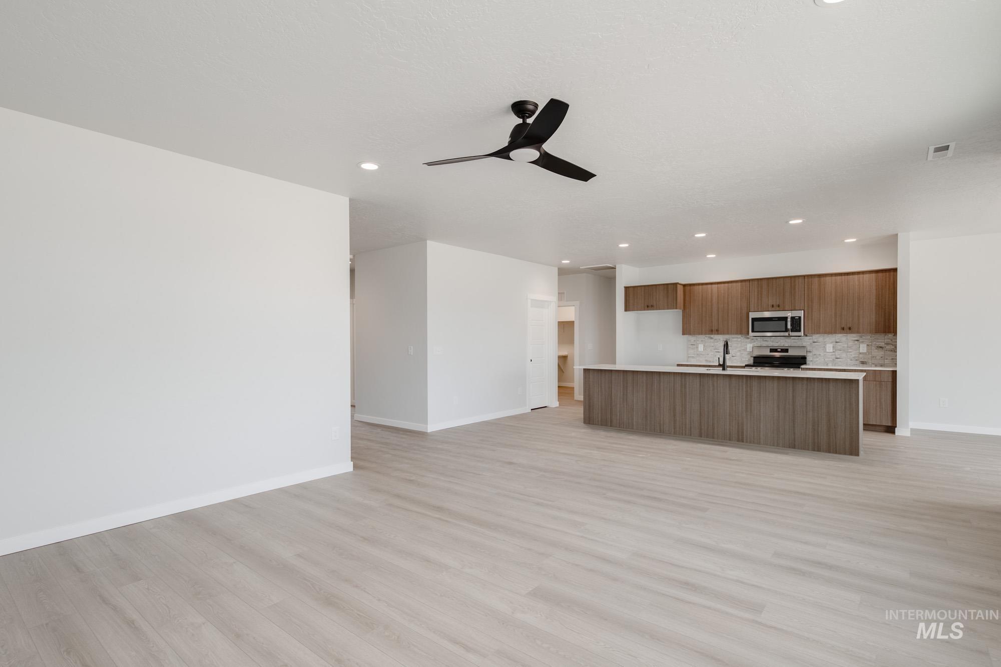 Kitchen with open floor plan, light wood-style flooring, brown cabinetry, recessed lighting, and light countertops