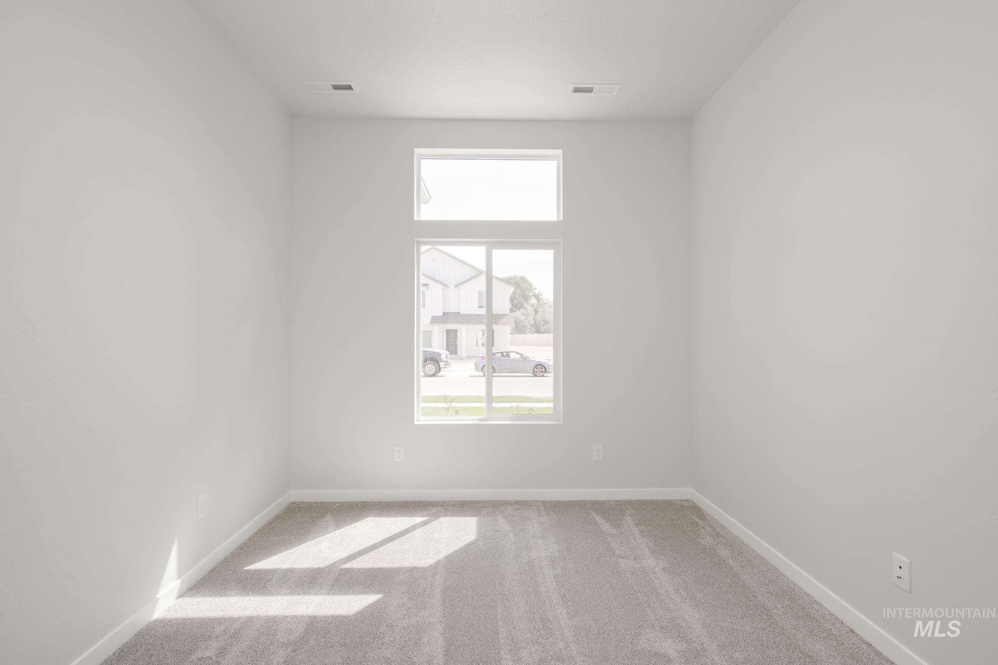 Carpeted spare room featuring baseboards