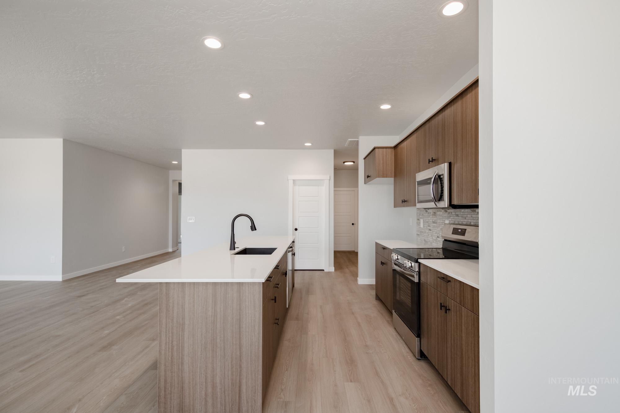 Kitchen with appliances with stainless steel finishes, modern cabinets, a kitchen island with sink, light wood-style floors, and recessed lighting