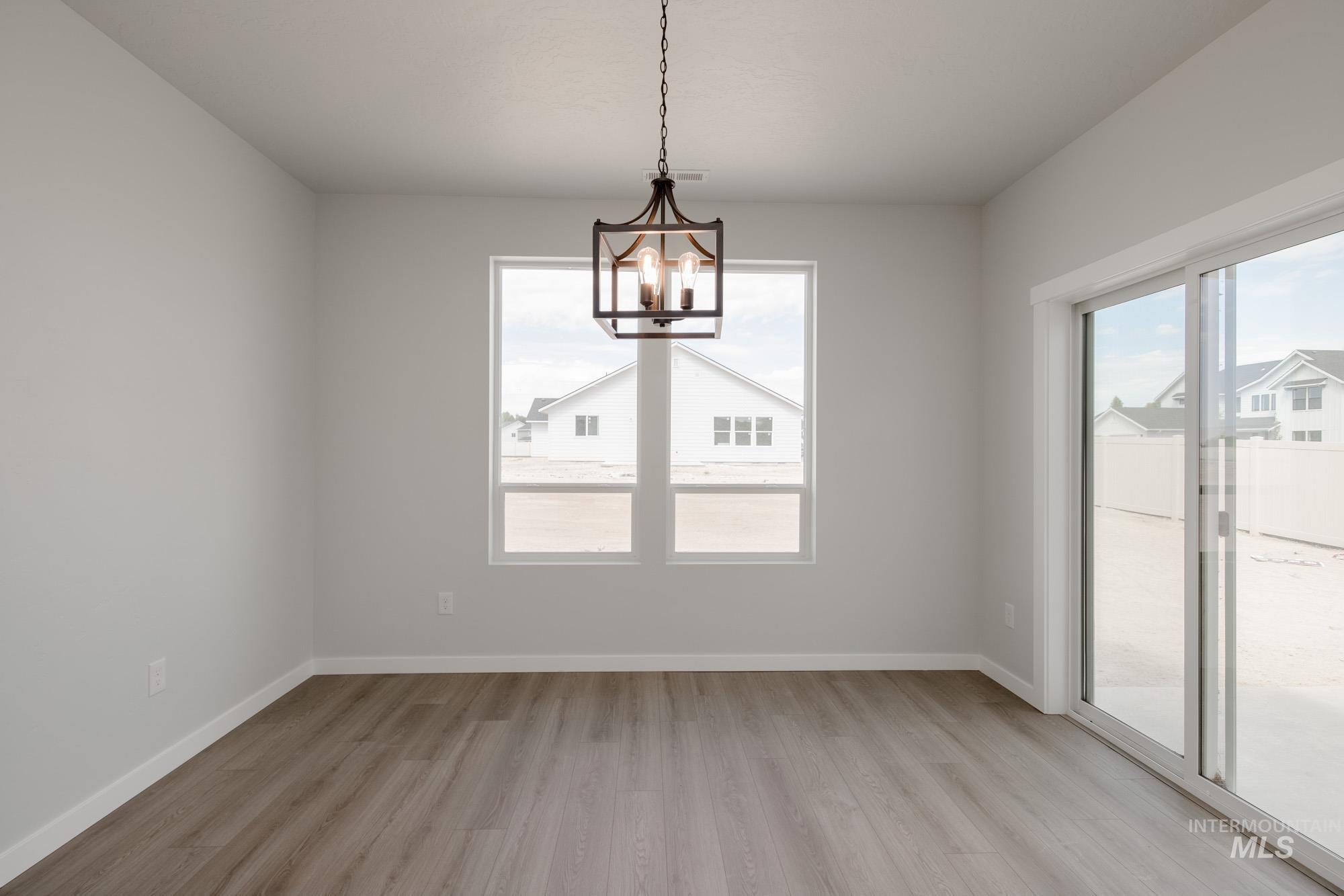 Unfurnished dining area featuring light wood-type flooring, plenty of natural light, and a chandelier