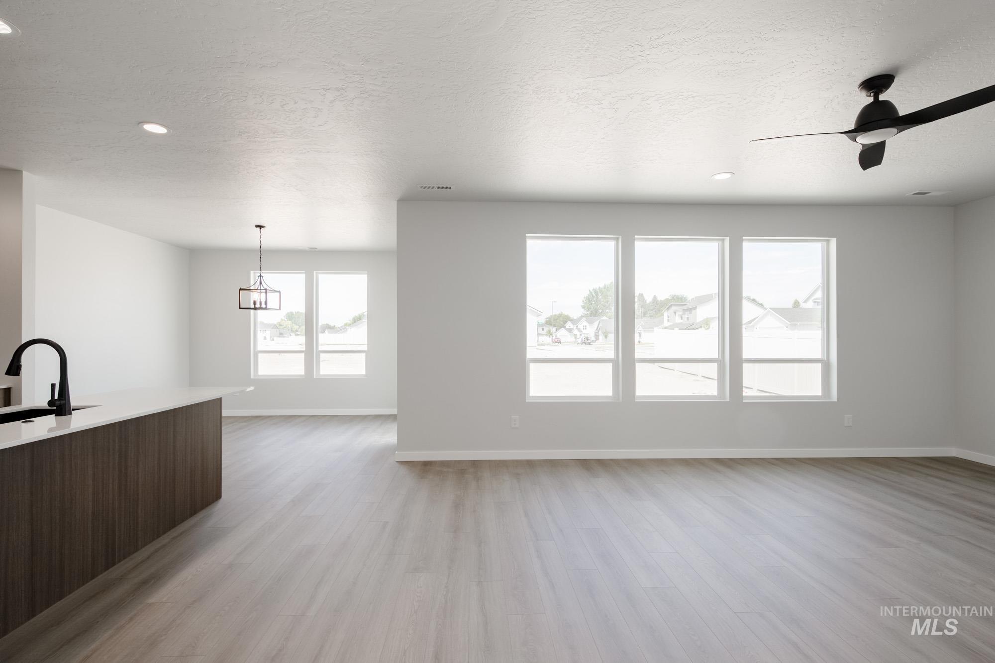 Unfurnished living room with light wood-type flooring, a textured ceiling, ceiling fan, and recessed lighting