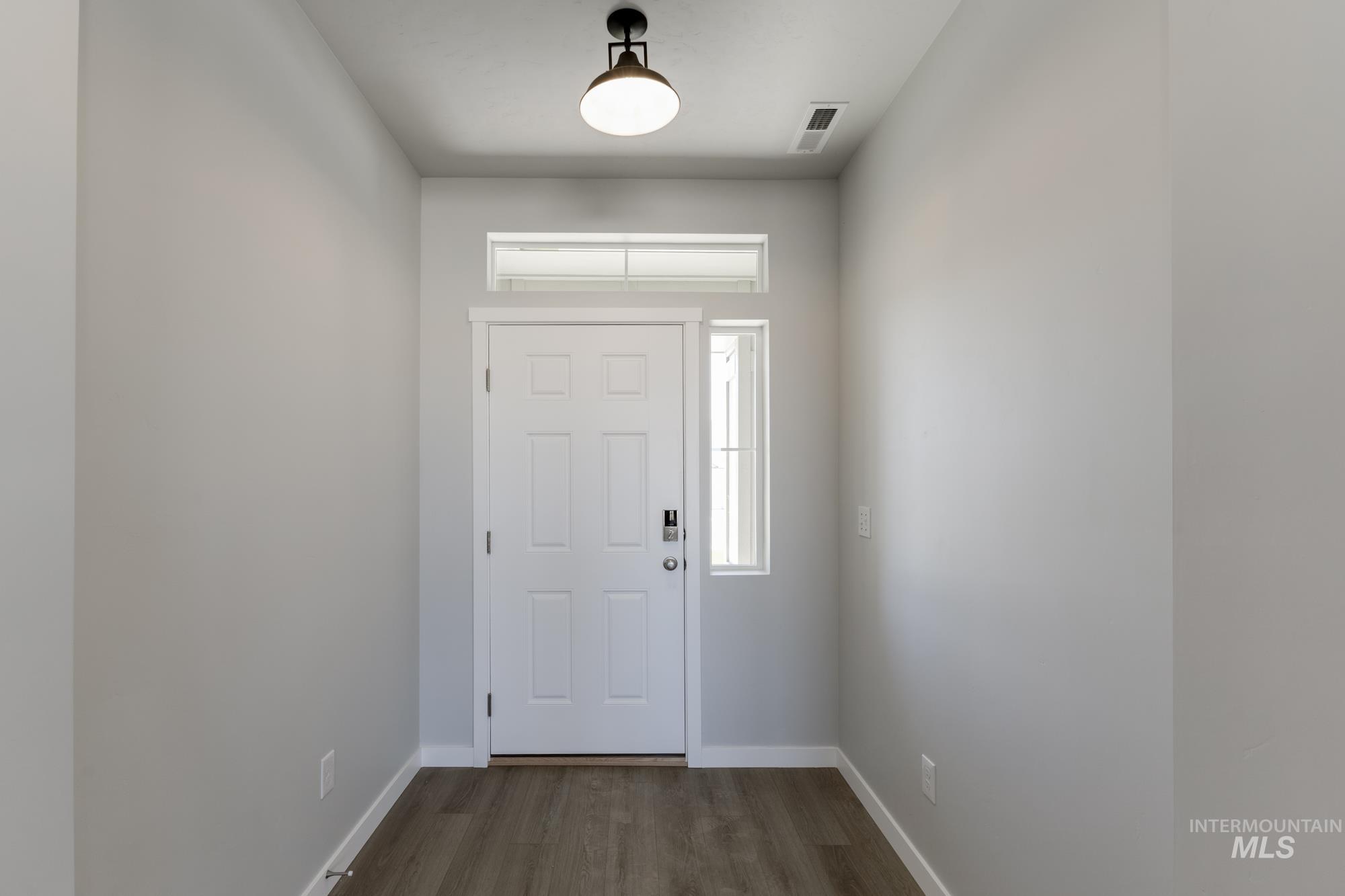 Entrance foyer with dark wood-style flooring and baseboards